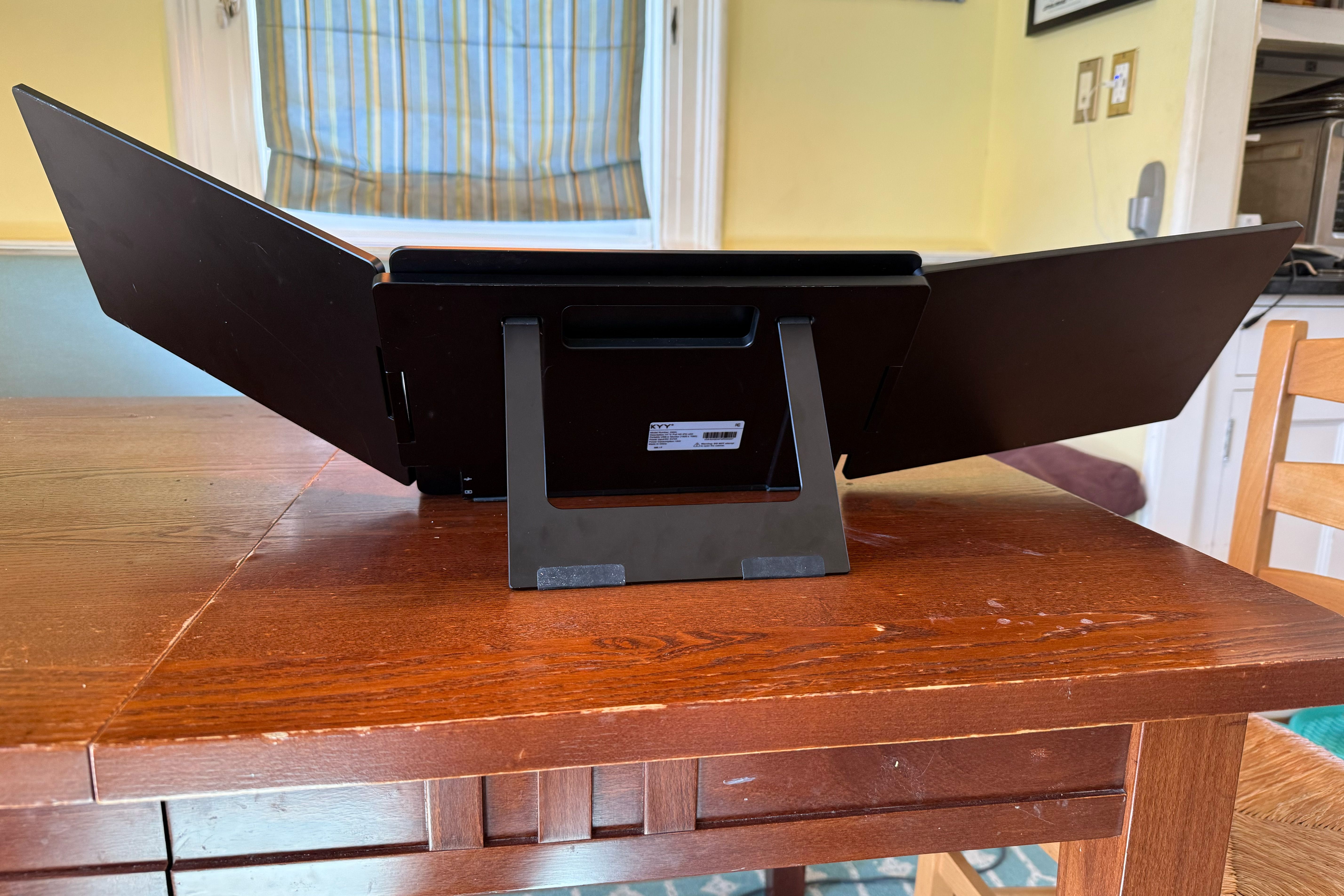 The back of the KYY triple monitor setup on a brown kitchen table.