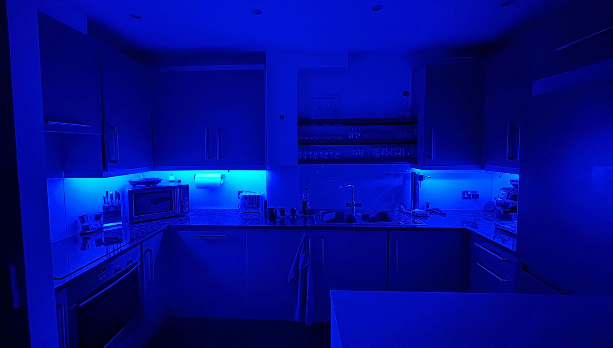 Cool blue lighting in an alcove kitchen.