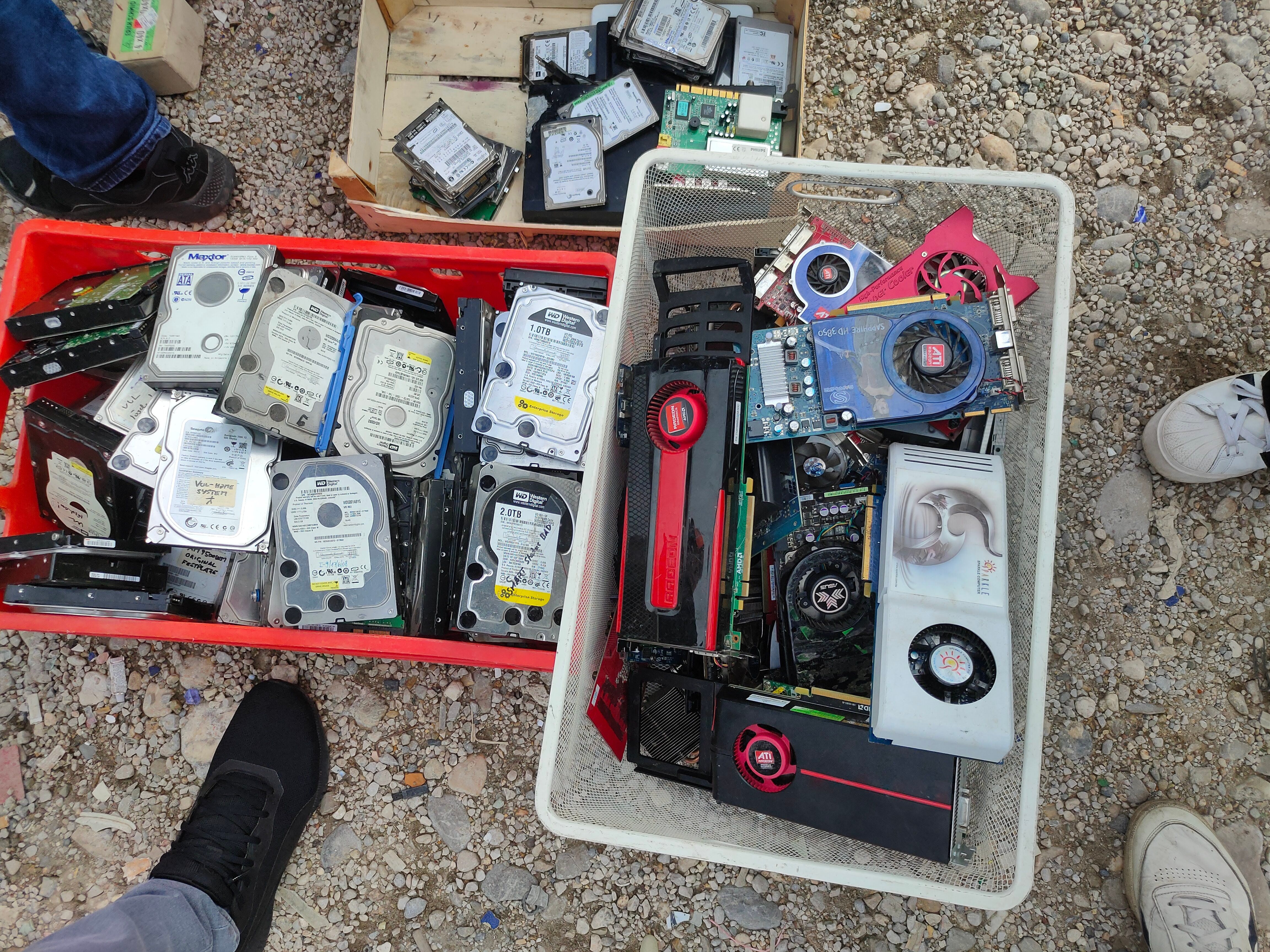 Plastic containers filled with old hard drives and graphics card at a flea market.