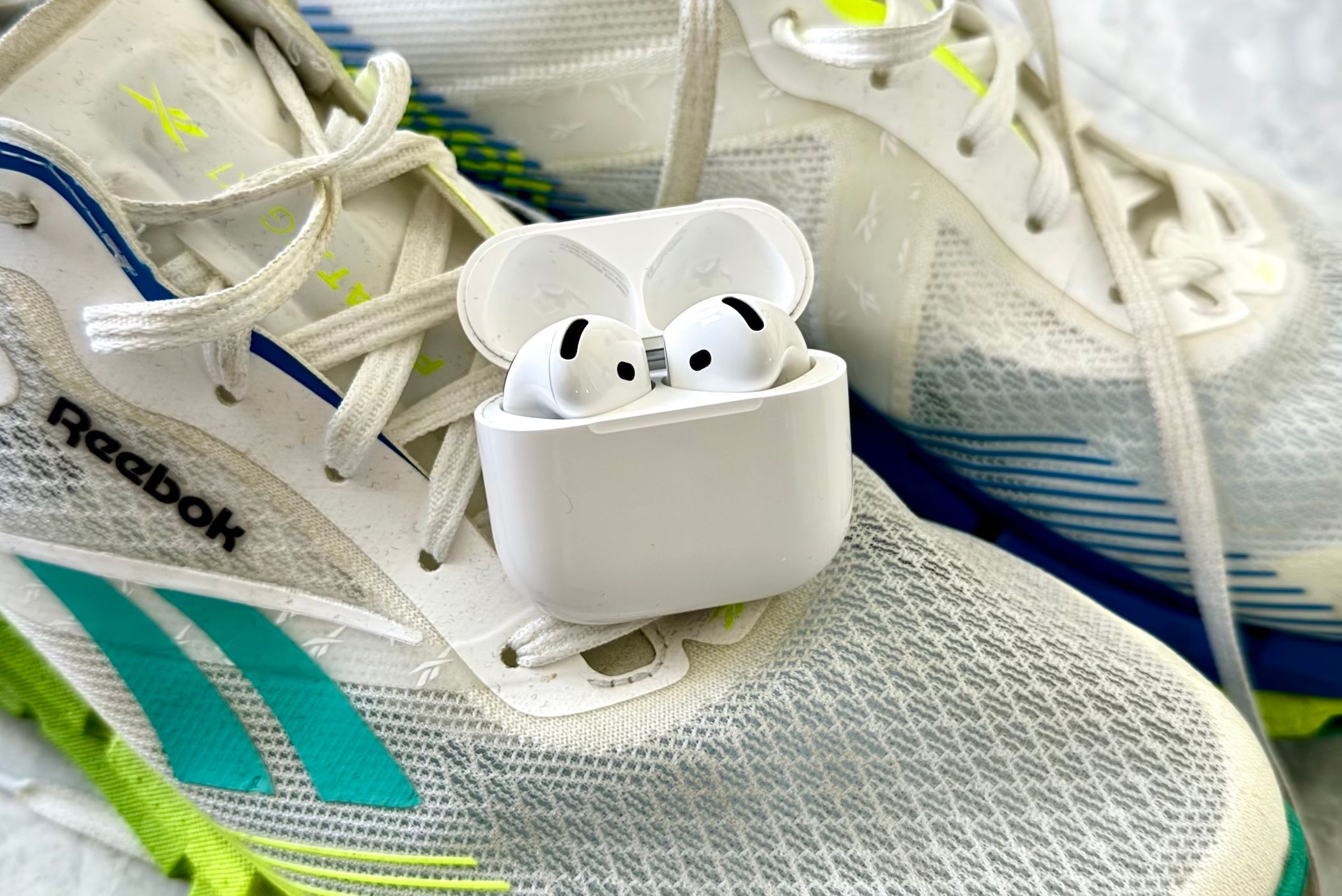 AirPods 4 sitting on a pair of running shoes