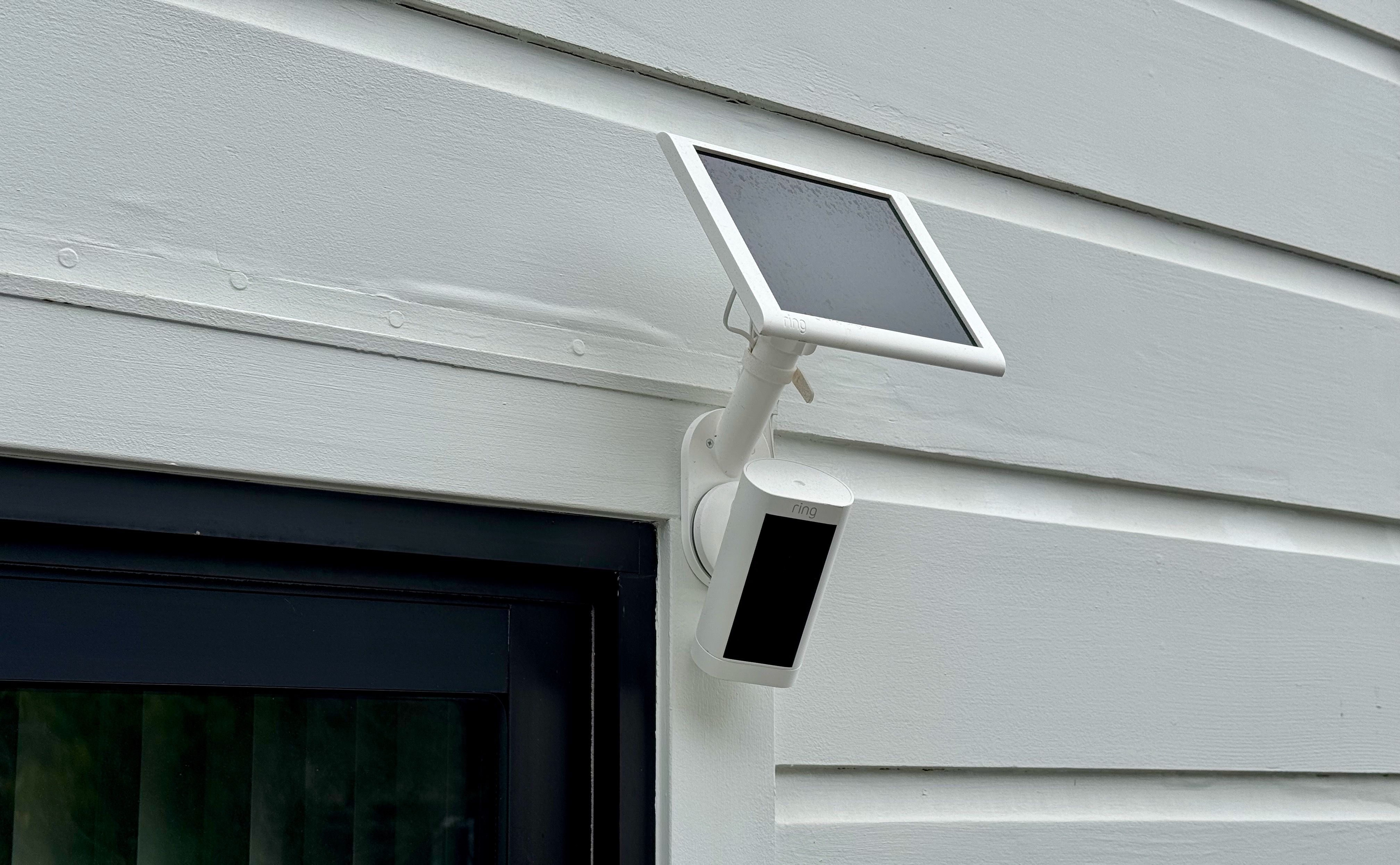 a Ring camera mounted on wall with solar panel.