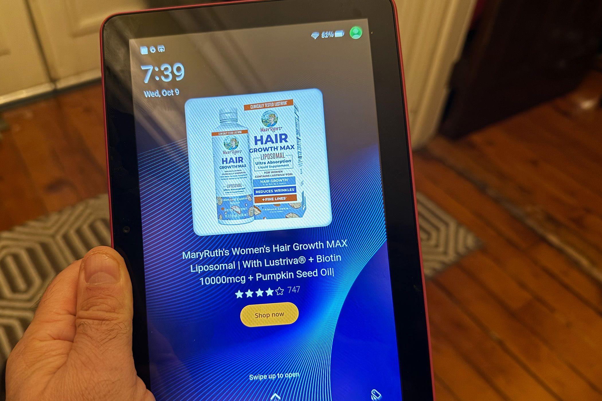 An Amazon Fire HD 8 in a hand, showing an advertisement for MaryRuth's Hair Growth formula. 