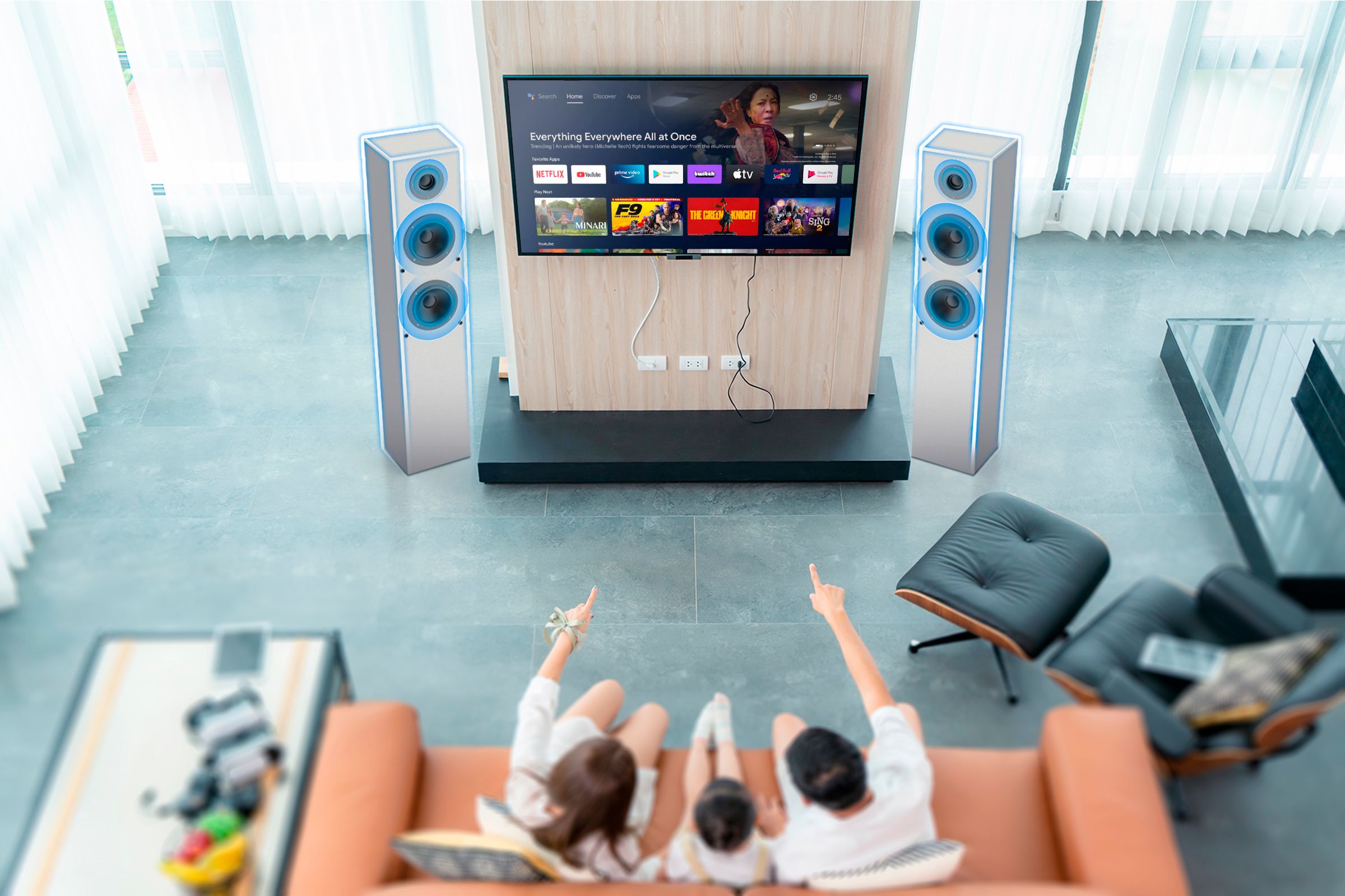 A family sitting on the couch watching TV with the speakers highlighted.