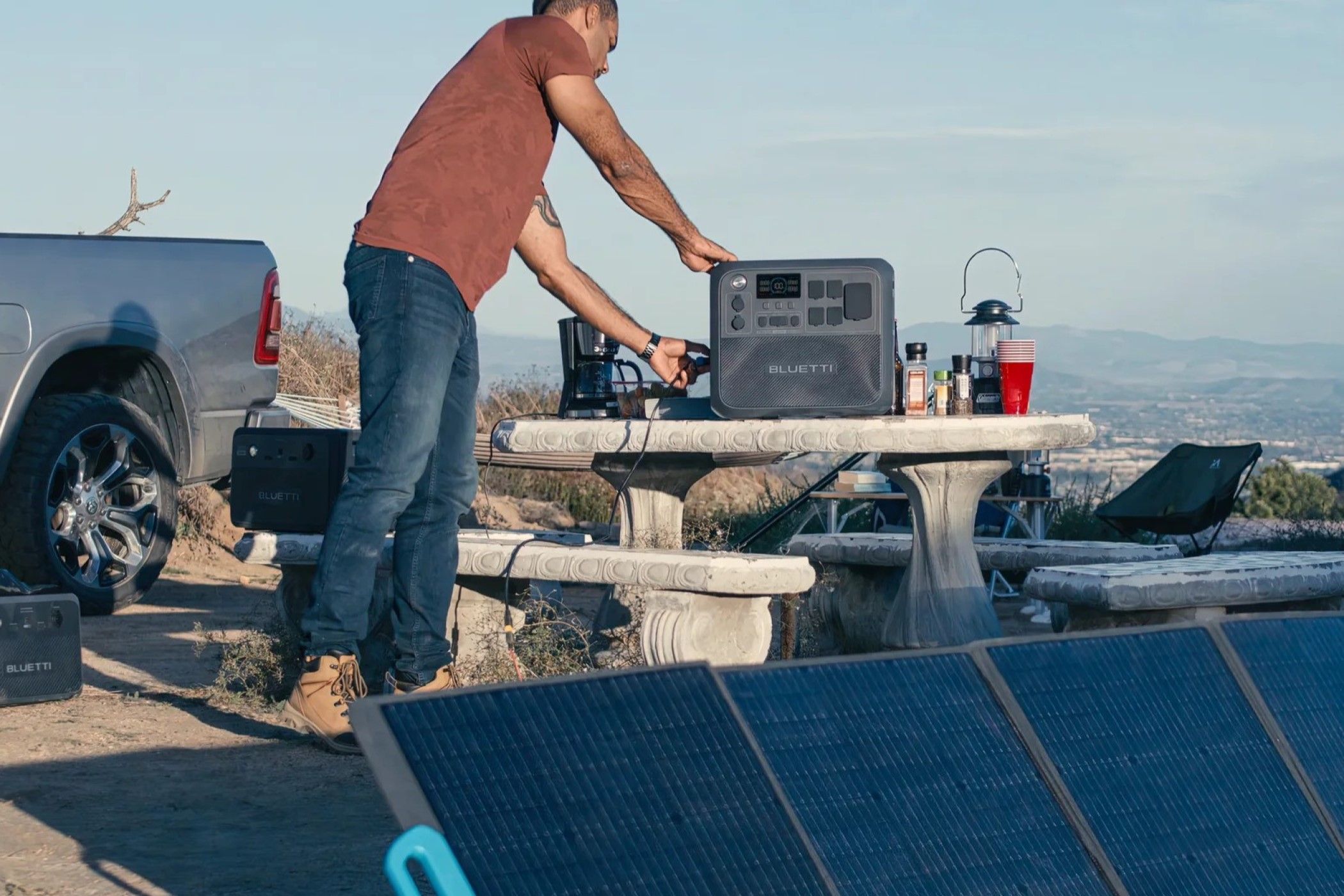 A person using their BLUETTI AC200L Portable Power Station to power multiple appliances while charging the power station with a solar panel. 