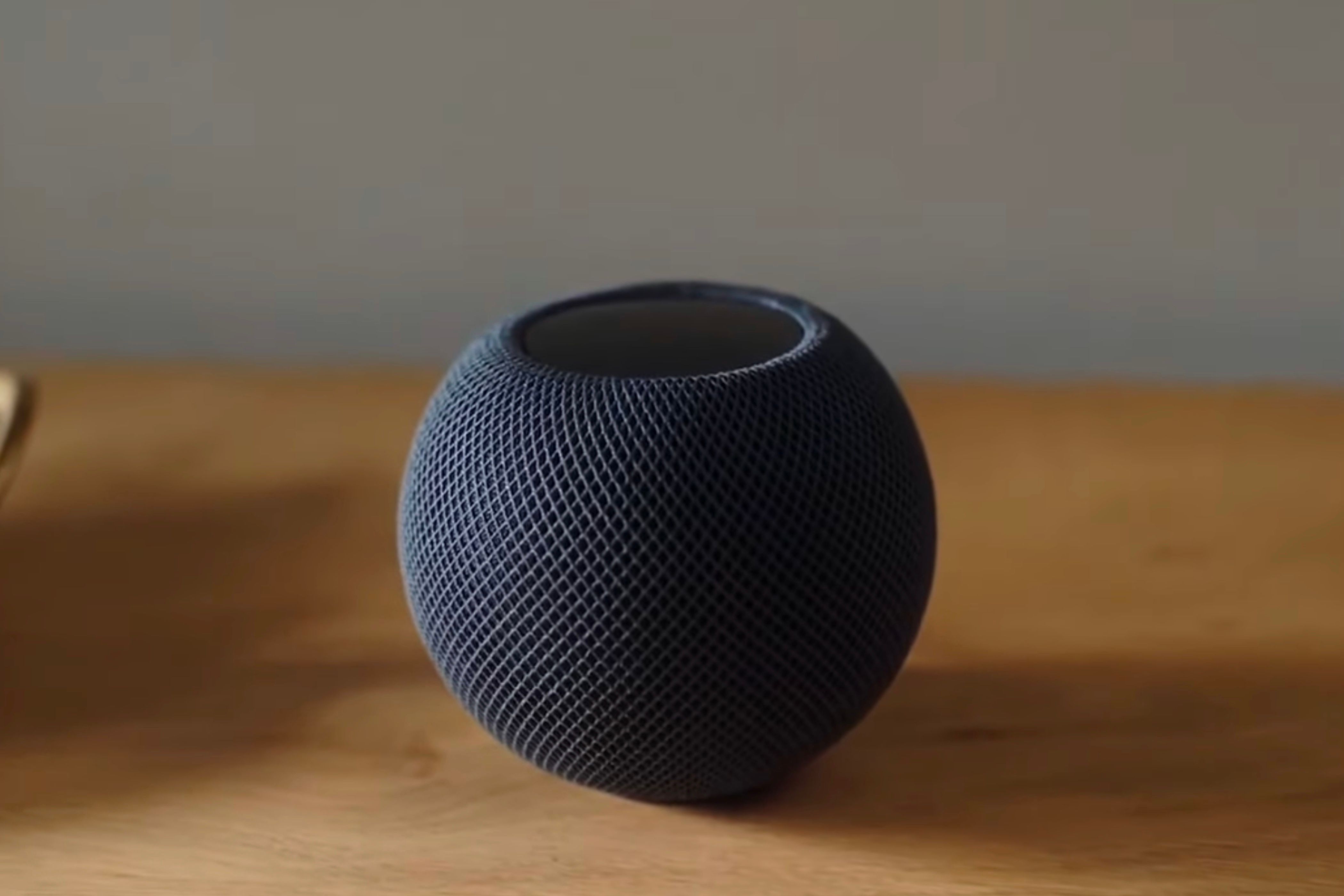 Black HomePod Mini sitting on a wooden table top