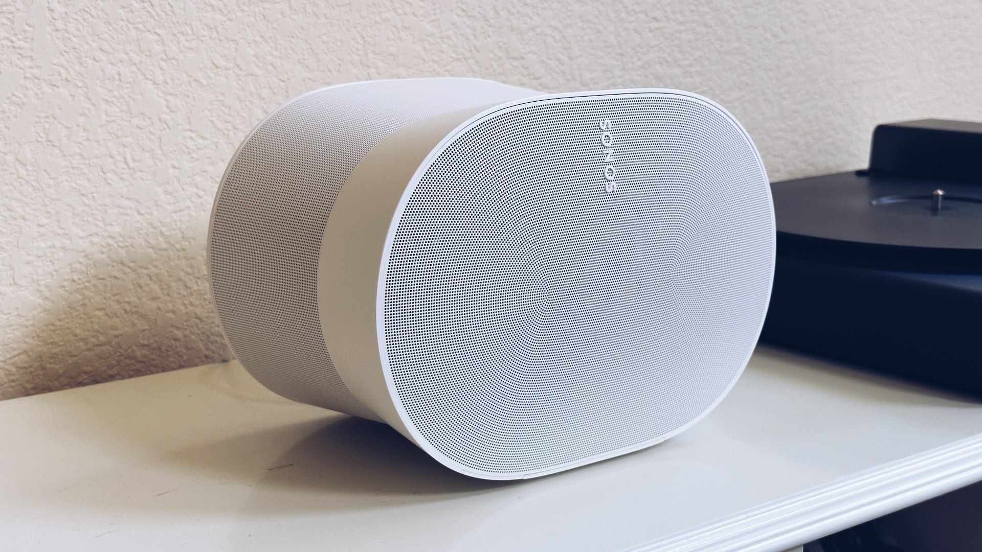 Sonos Era 300 in white sitting on a shelf next to a record player.