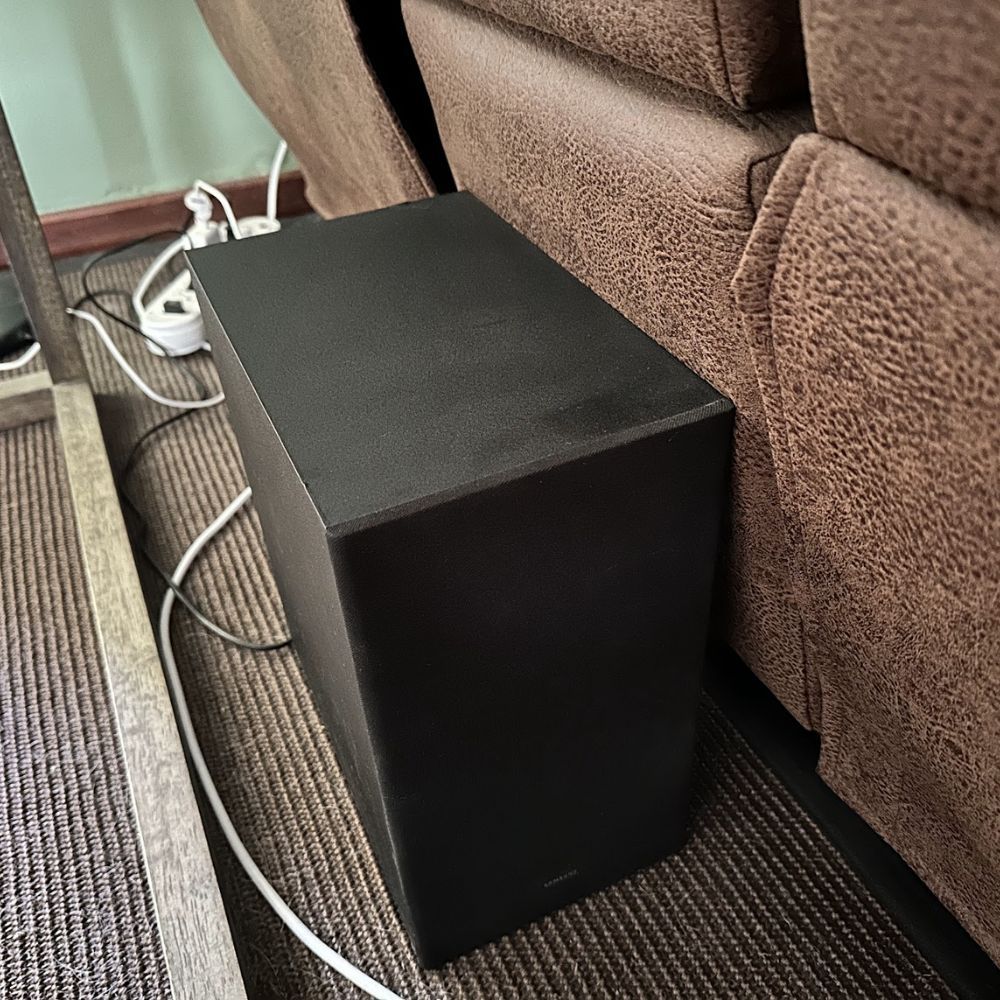 Subwoofer set up against the back of a couch.