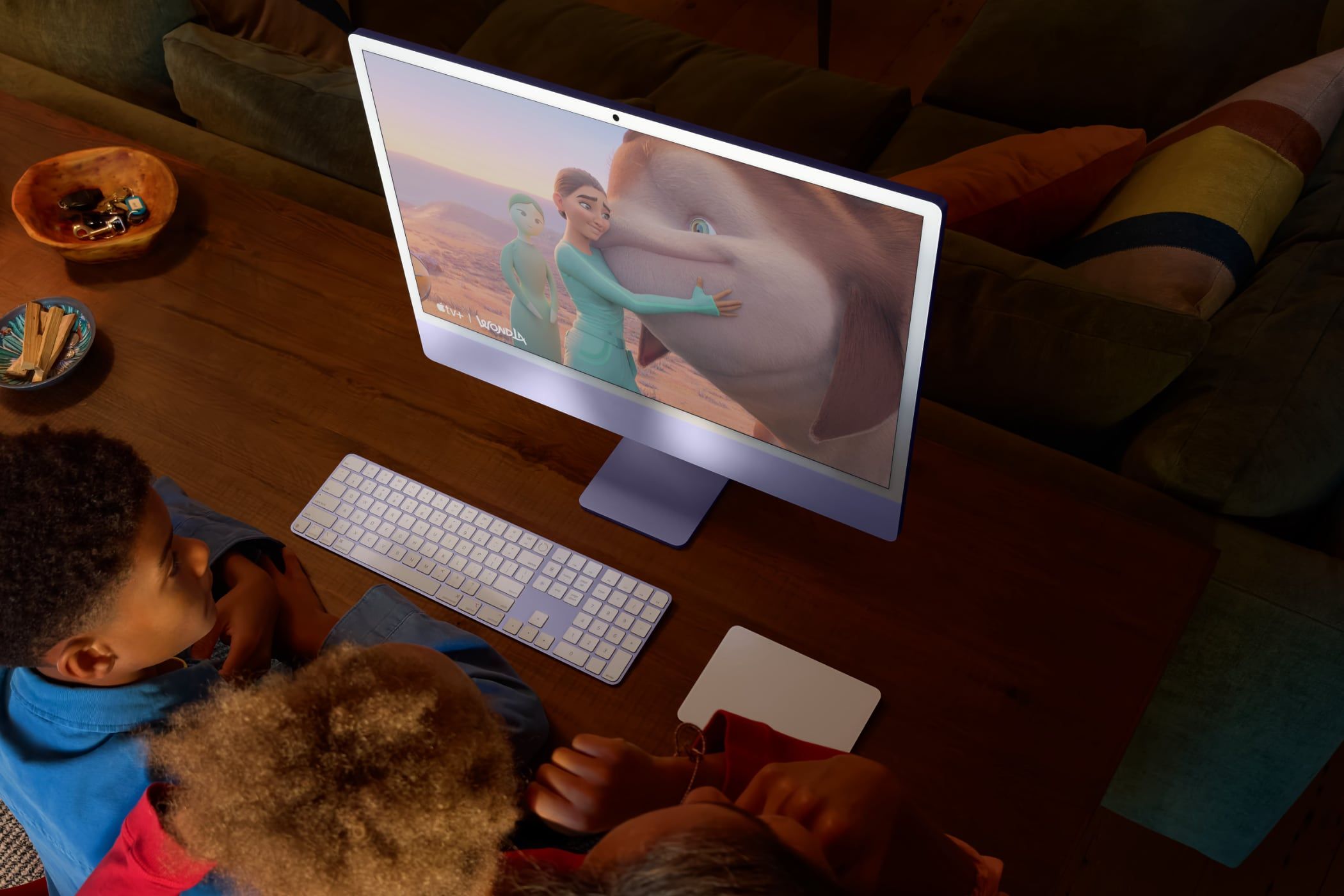 People grouped around a 24-inch iMac, looking at the screen.