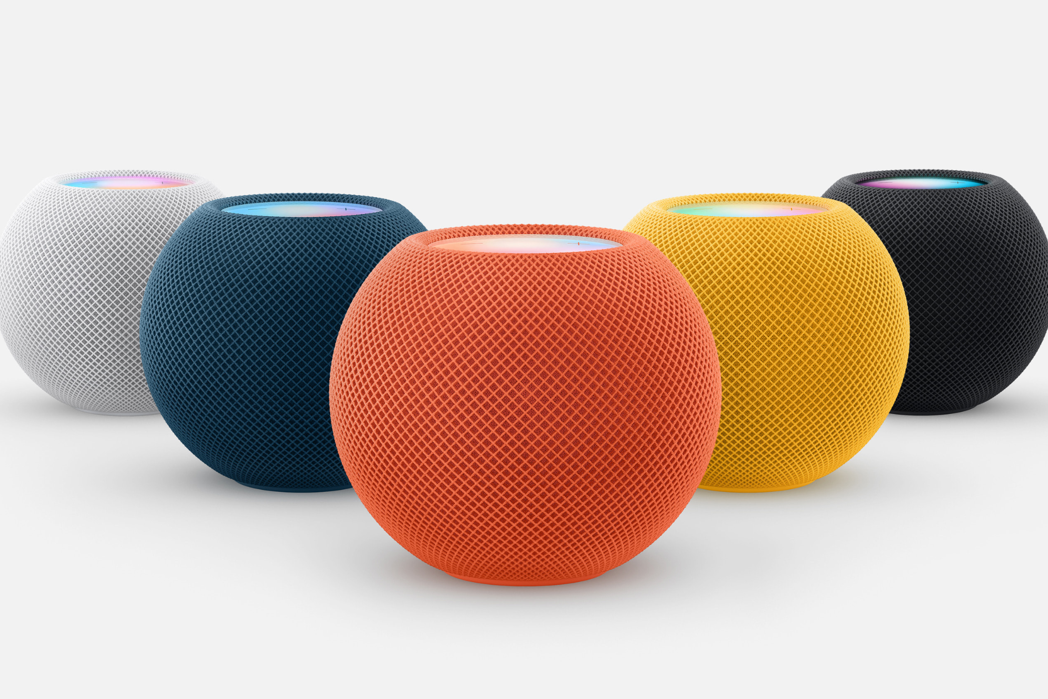 Apple's HomePod sitting on a white table in all colors.