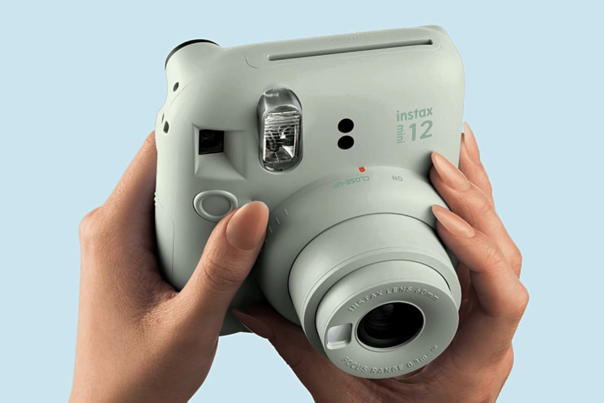 A mint green Fujifilm Instax Mini 12 in someone's hands.