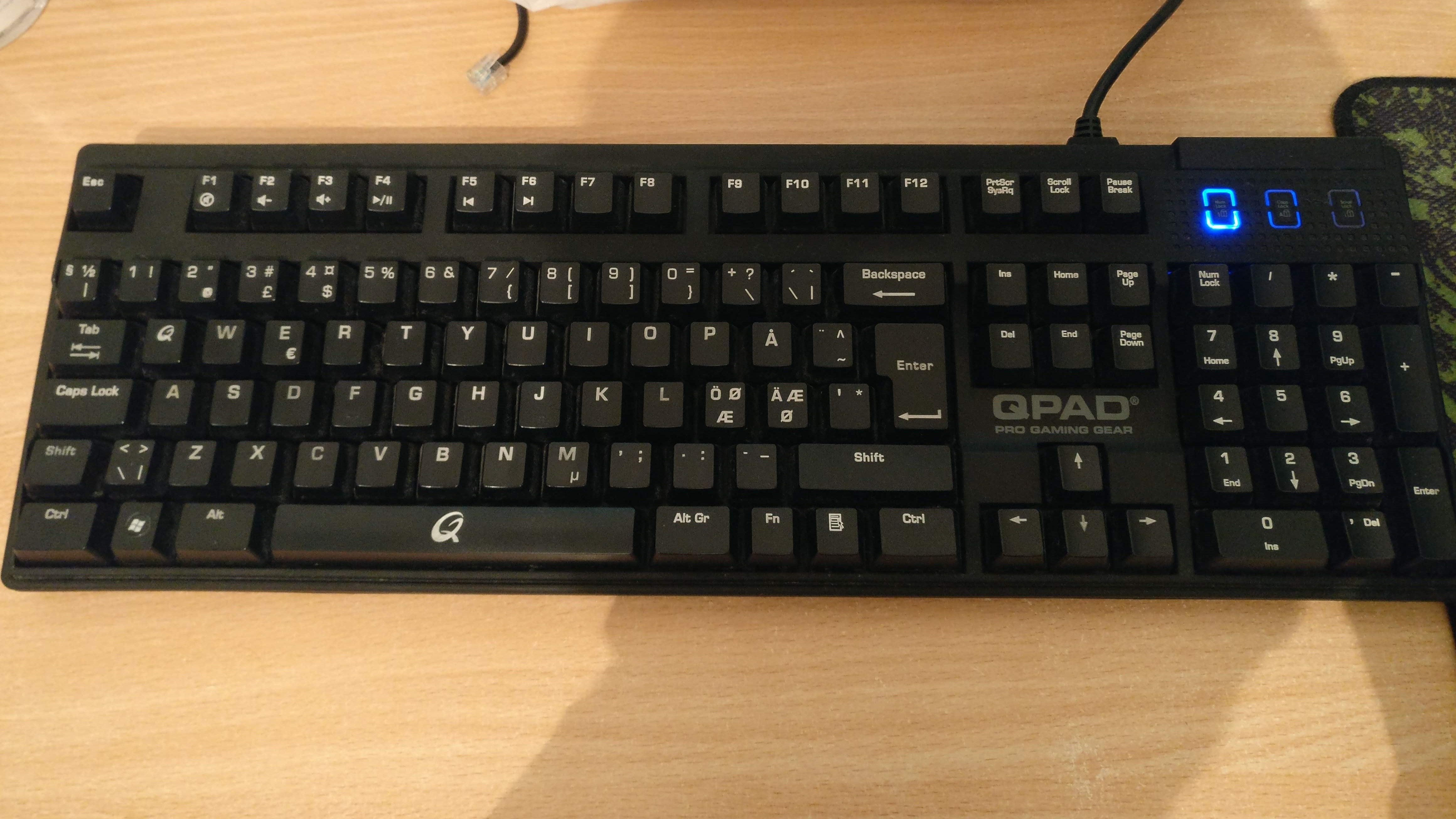 The QPAD MK-50 mechanical keyboard on a wooden desk.