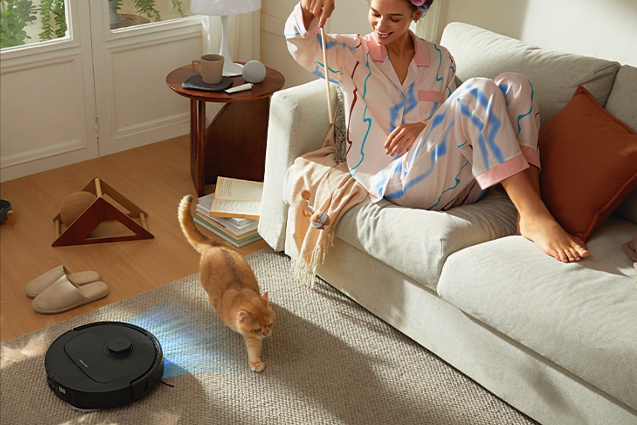 A woman plays with her cat as the Roborock Qrevo S goes about its cleaning business.