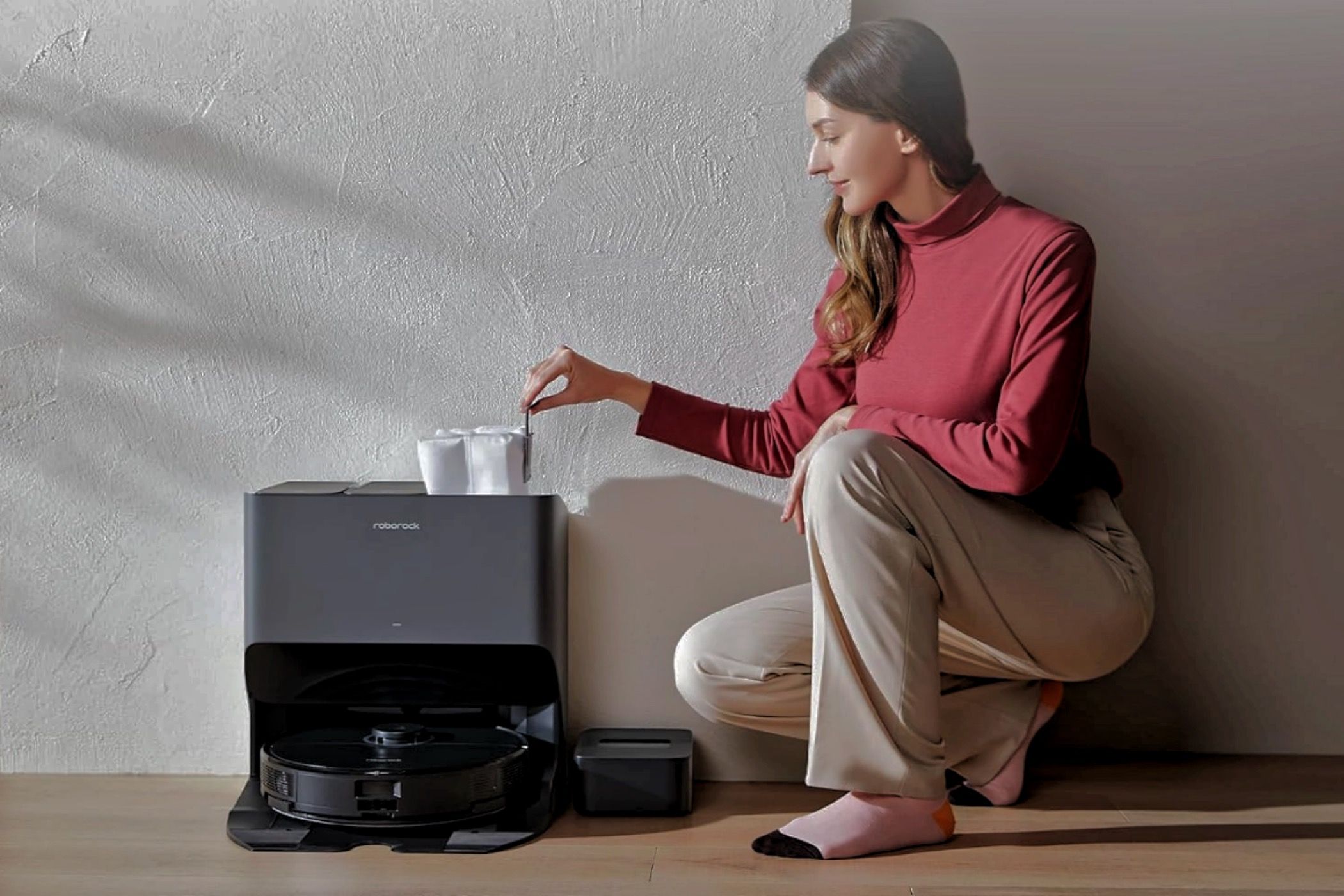 A woman changing the Roborock S8 Pro Ultra's dust bag.