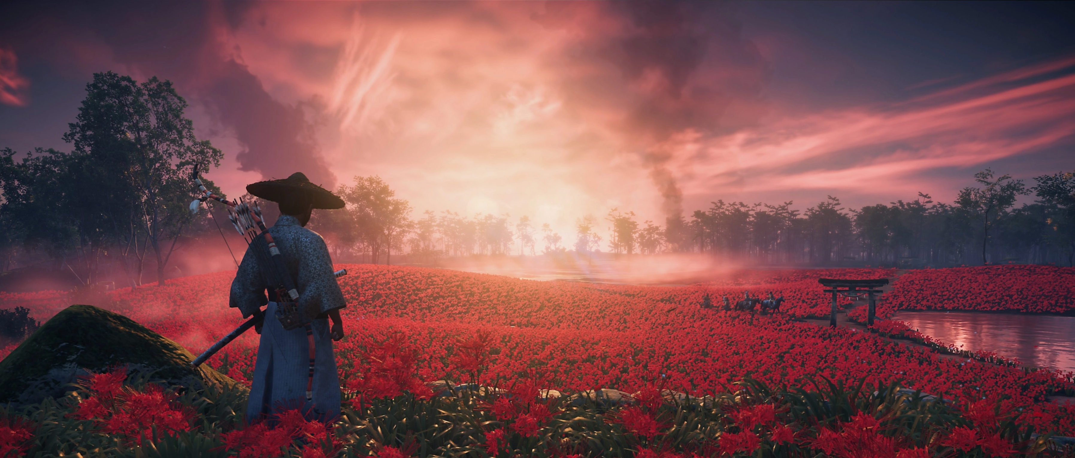 Jin looking over red flowers and a sunset in Ghost of Tsushima.