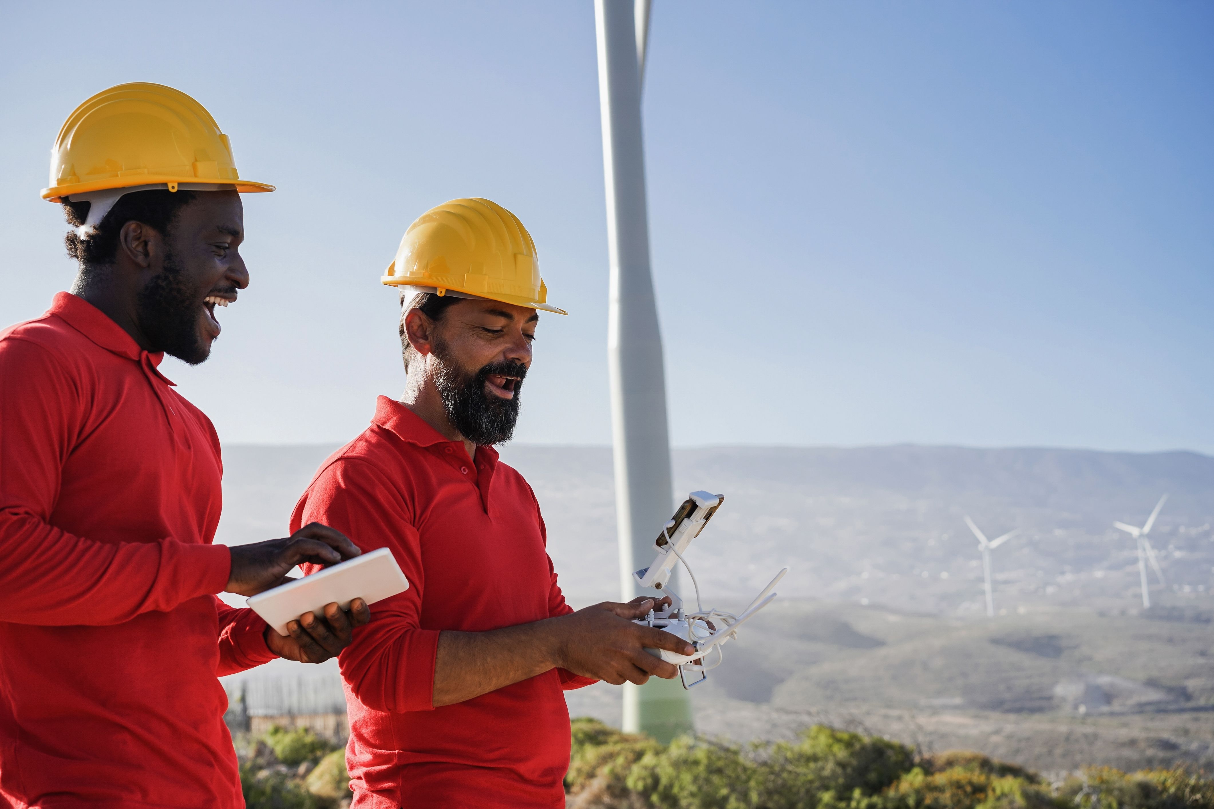 Multiracial engineer men working on windmill farm with digital tablet and drone.