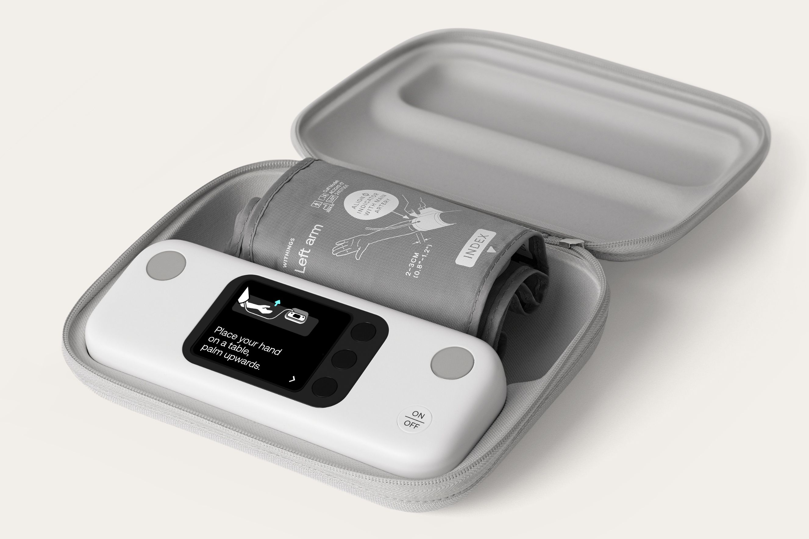 Withings BPM Vision blood pressure monitor in an open case alongside a rolled-up cuff.