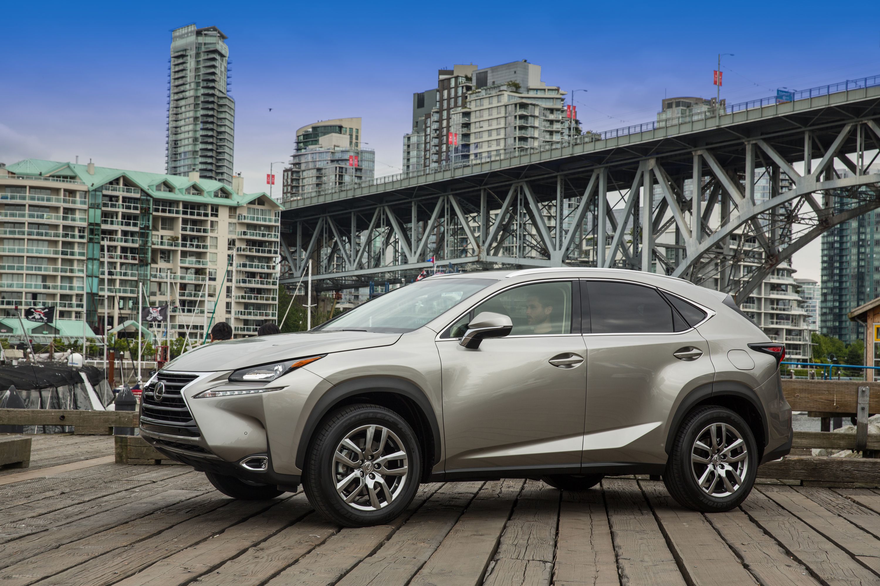 A gray 2015 Lexus NX 200t pictured parked at an angle in front of a bridge.