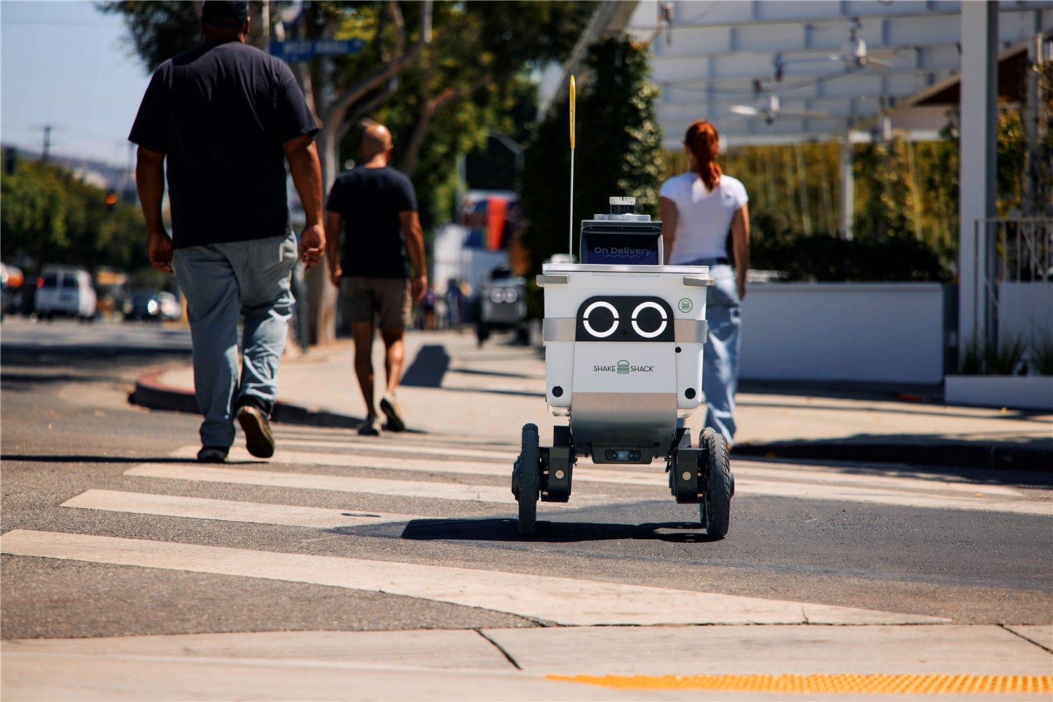 A Serve Robotics sidewalk robot crossing the road.