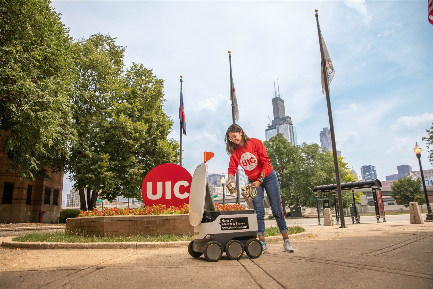 A Starship sidewalk robot delivering food to a girl at the University of Illinois Chicago.