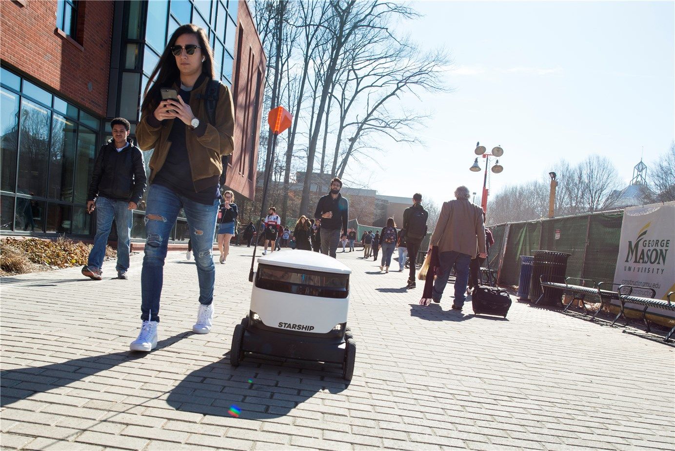 A Starship sidewalk Robot sharing the road with pedestrians.