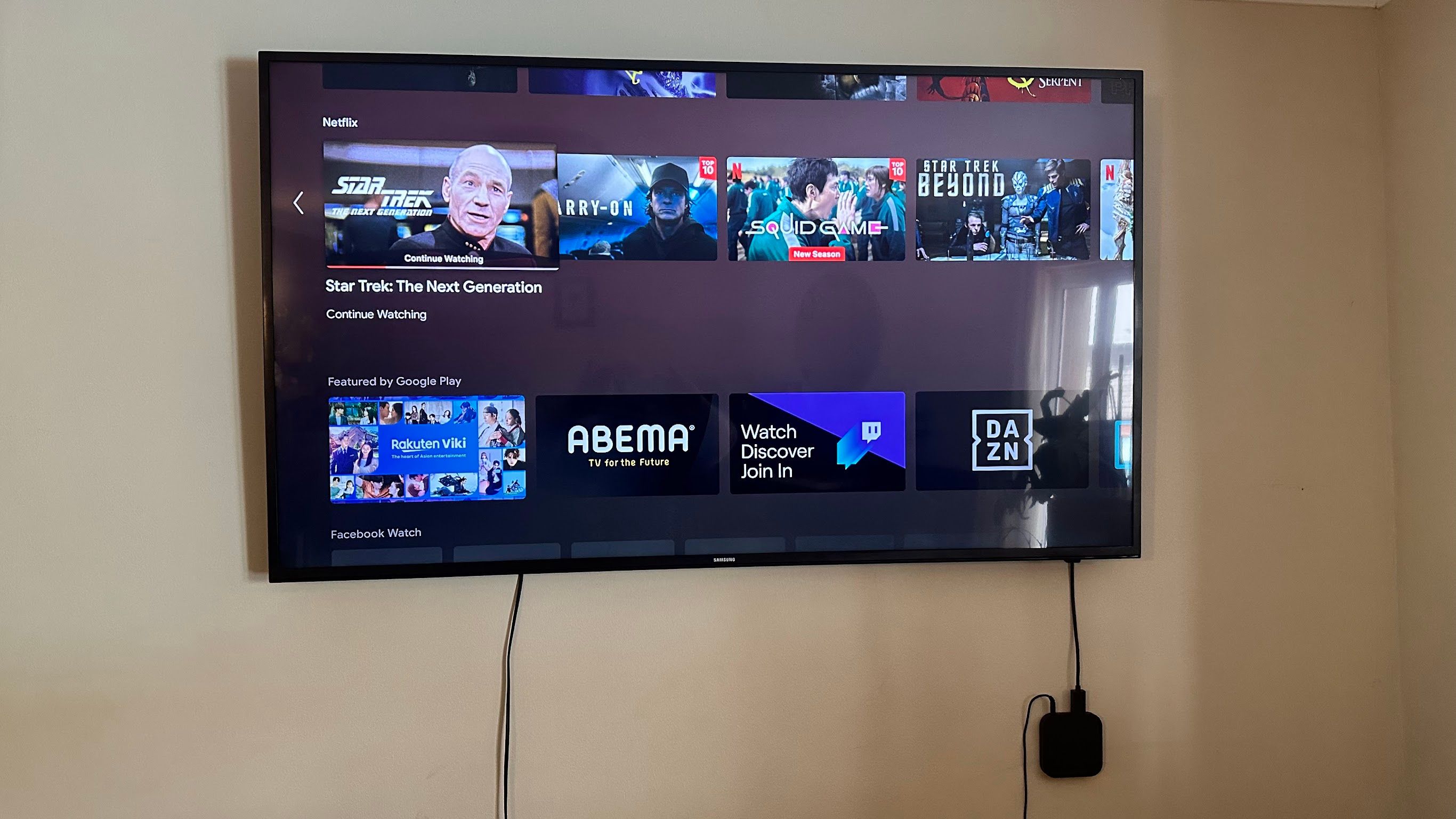 A wall-mounted TV with an Android streaming box attached.