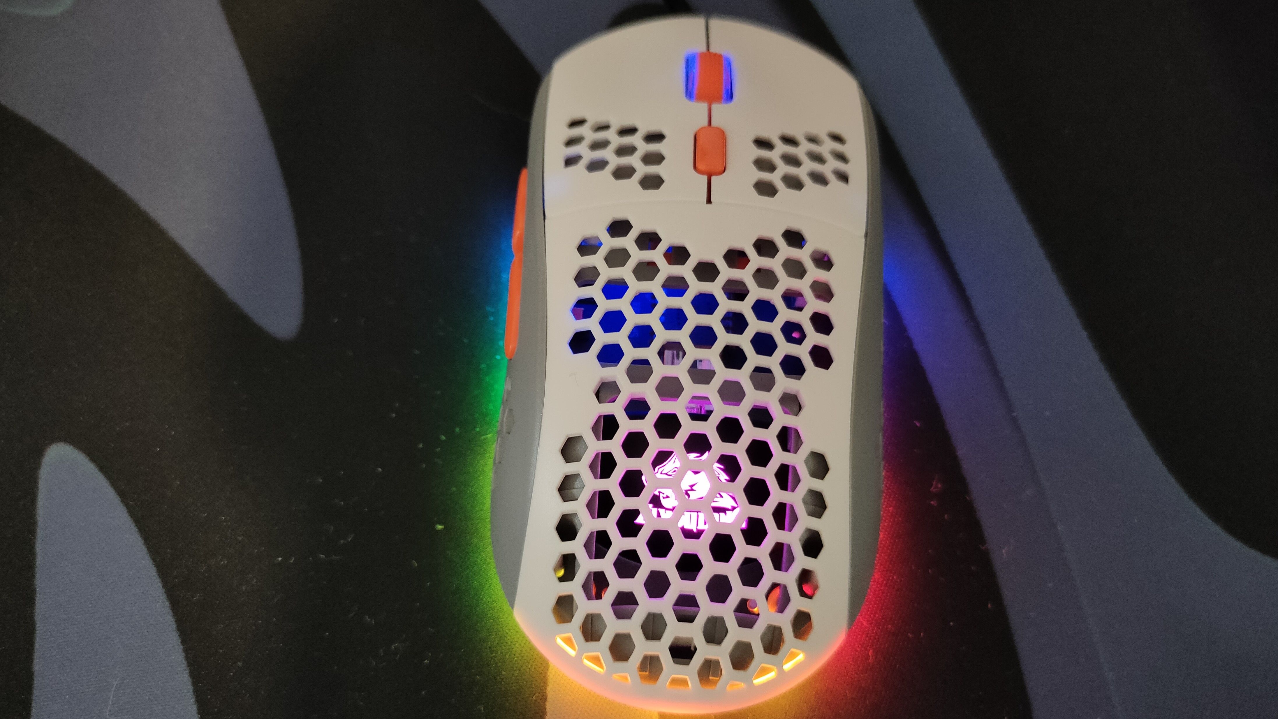 A white gaming mouse with holes and RGB.