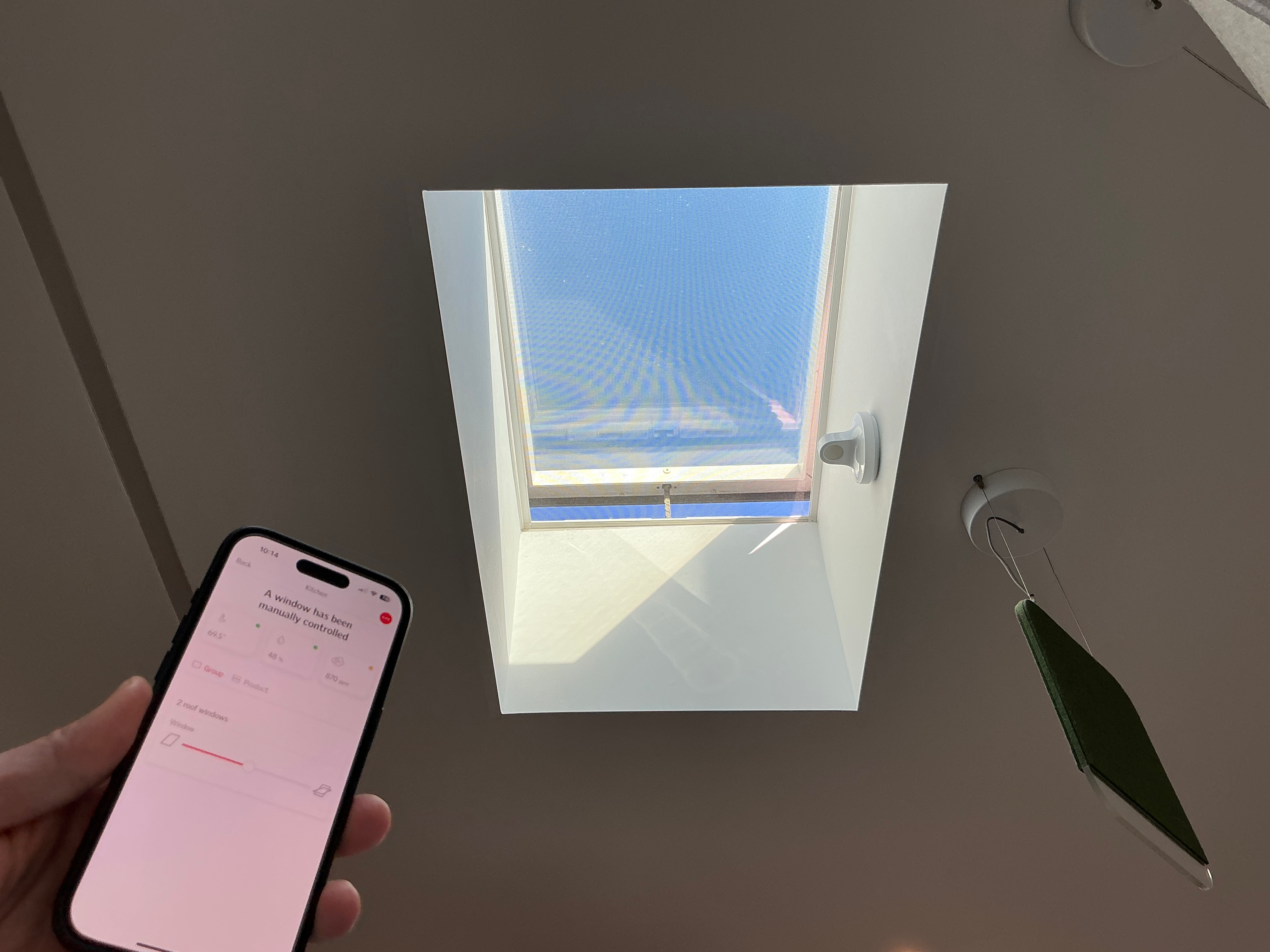 A Velux motorized window with smartphone in shot.