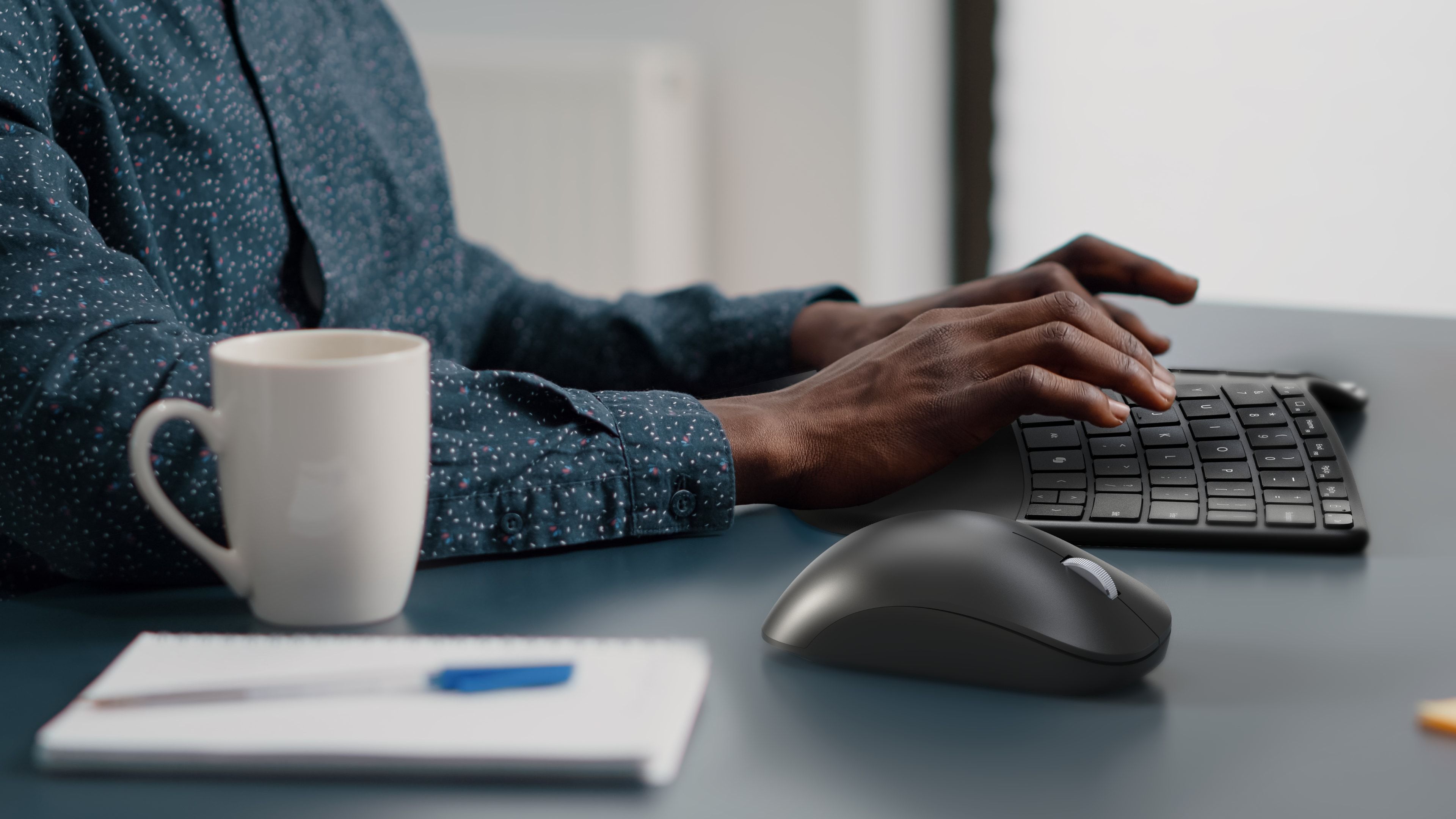 Side view of a male sitting at a work desk and typing on Incase's compact ergonomic keyboard.