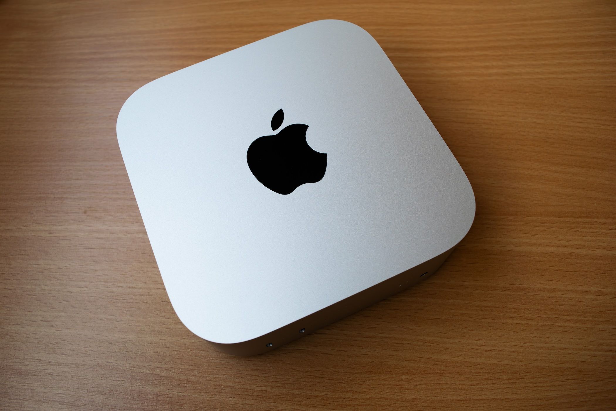 An M4 Mac Mini Sitting on a wooden table. 