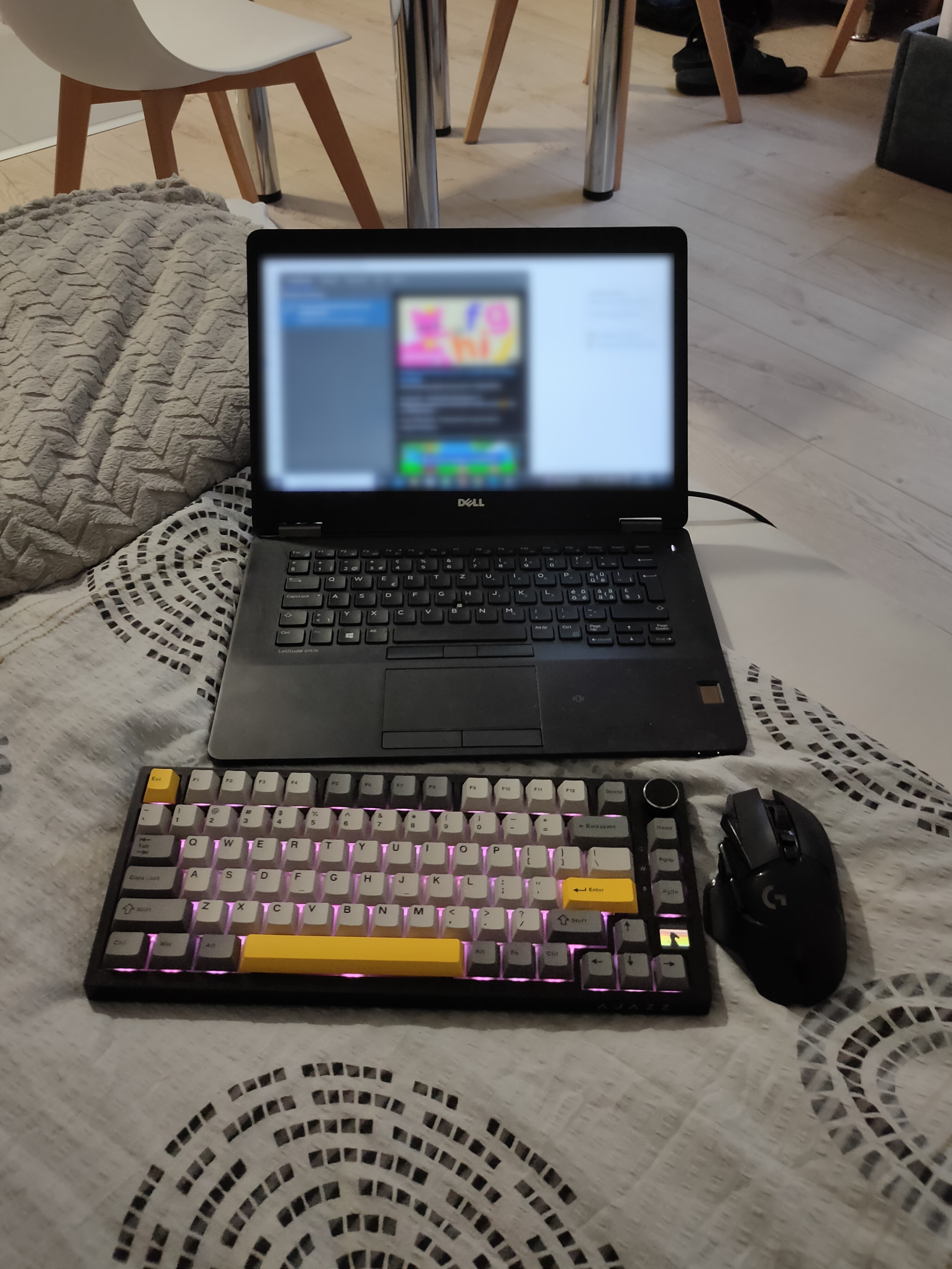 A wireless keyboard and mouse on a bed with a laptop.