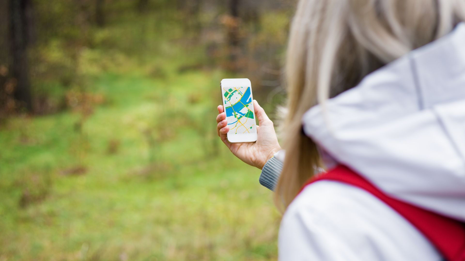 Woman geocaching in a forest using smartphone navigation app.