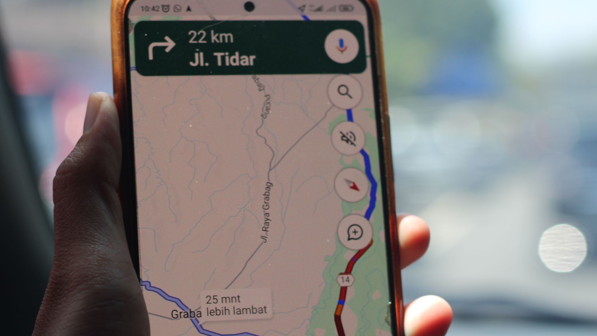 A person in a car holding their smartphone displaying Google Maps real-time traffic information.