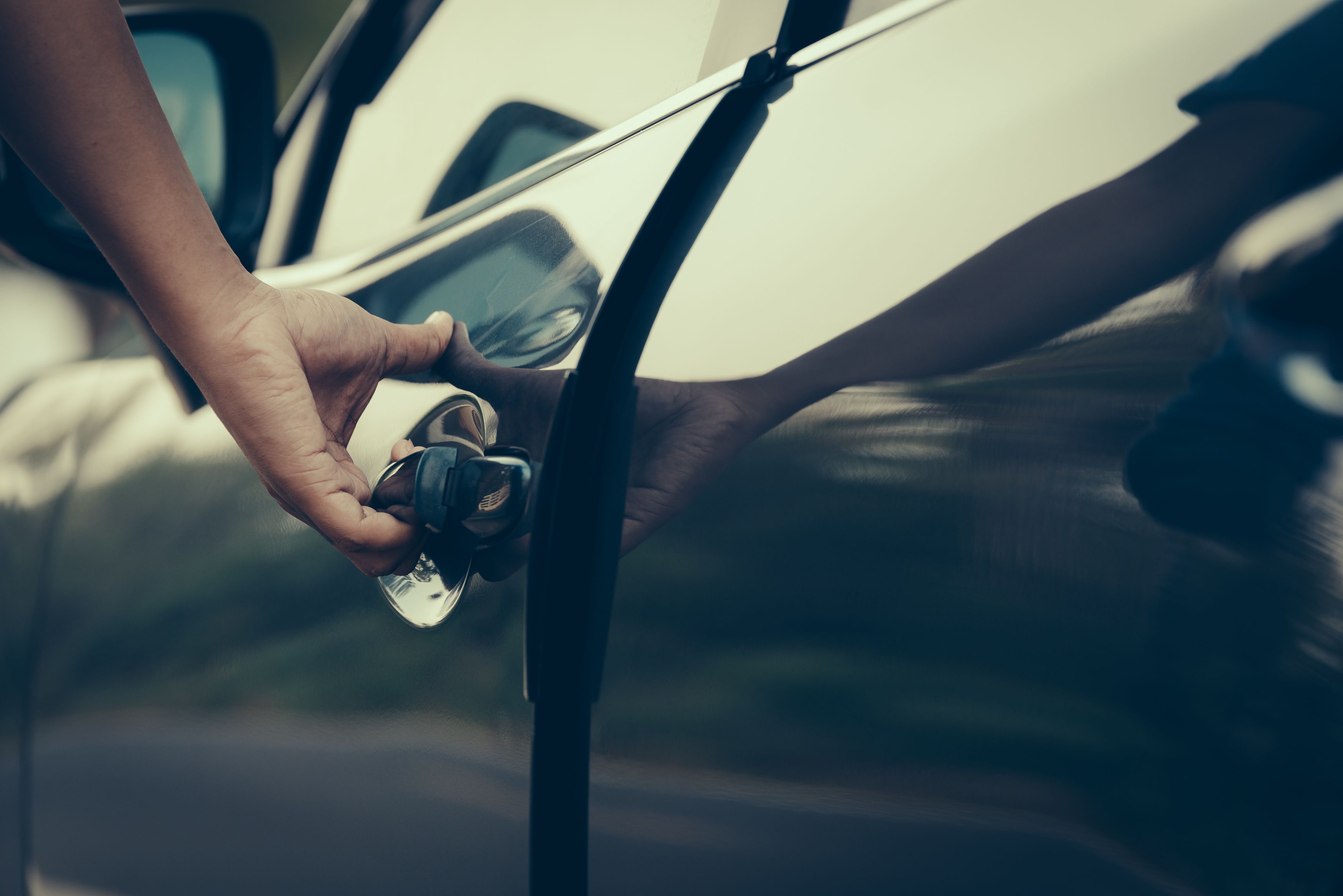 A person opening a car door without a key thanks to passive keyless entry.