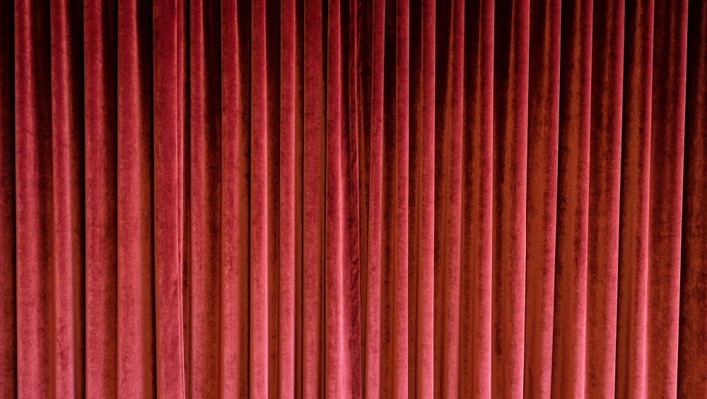 Heavy red velvet curtain in old fashioned theatre.