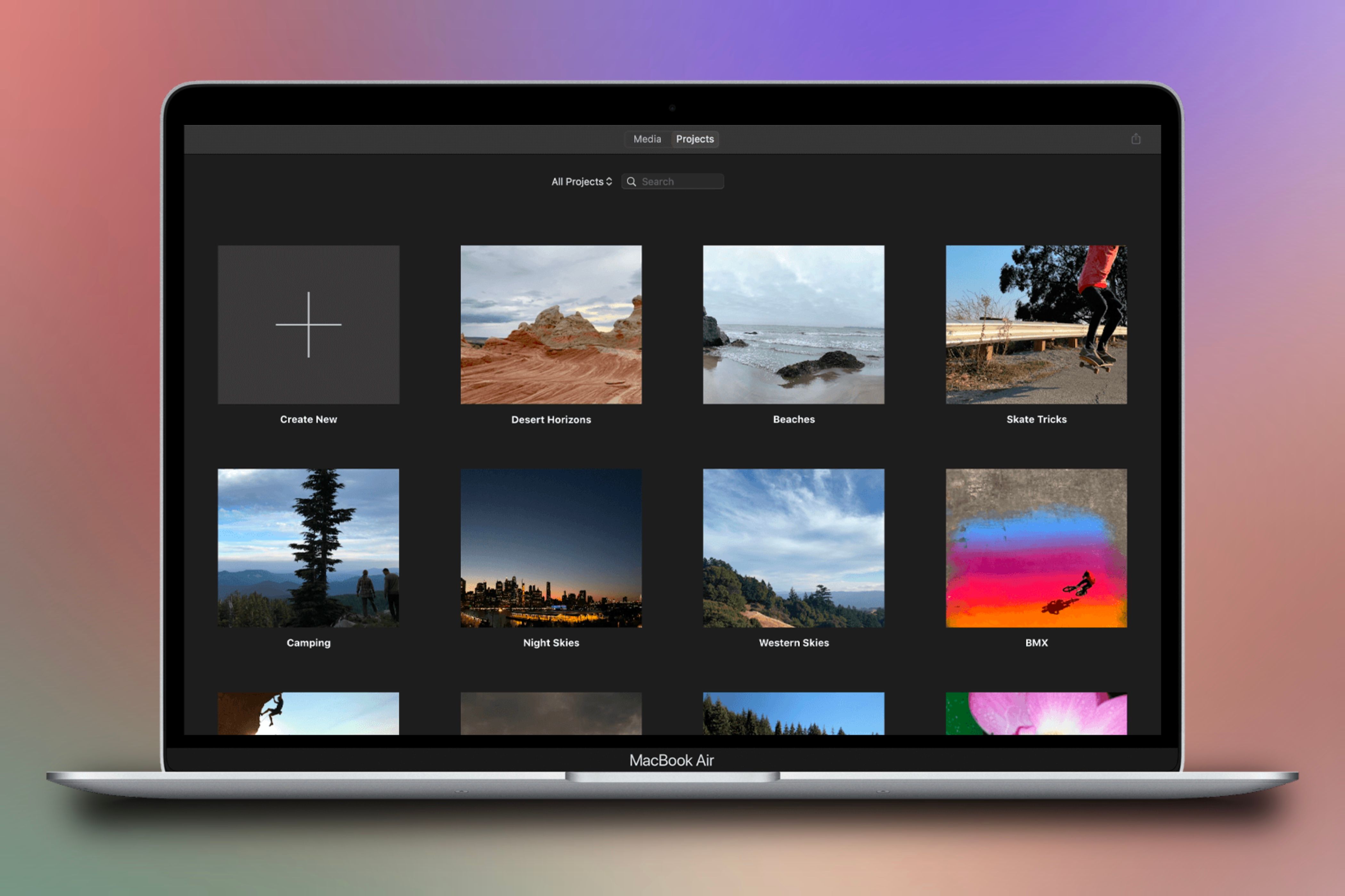 A MacBook showing the library of a iMovie projects in front of a colorful background.