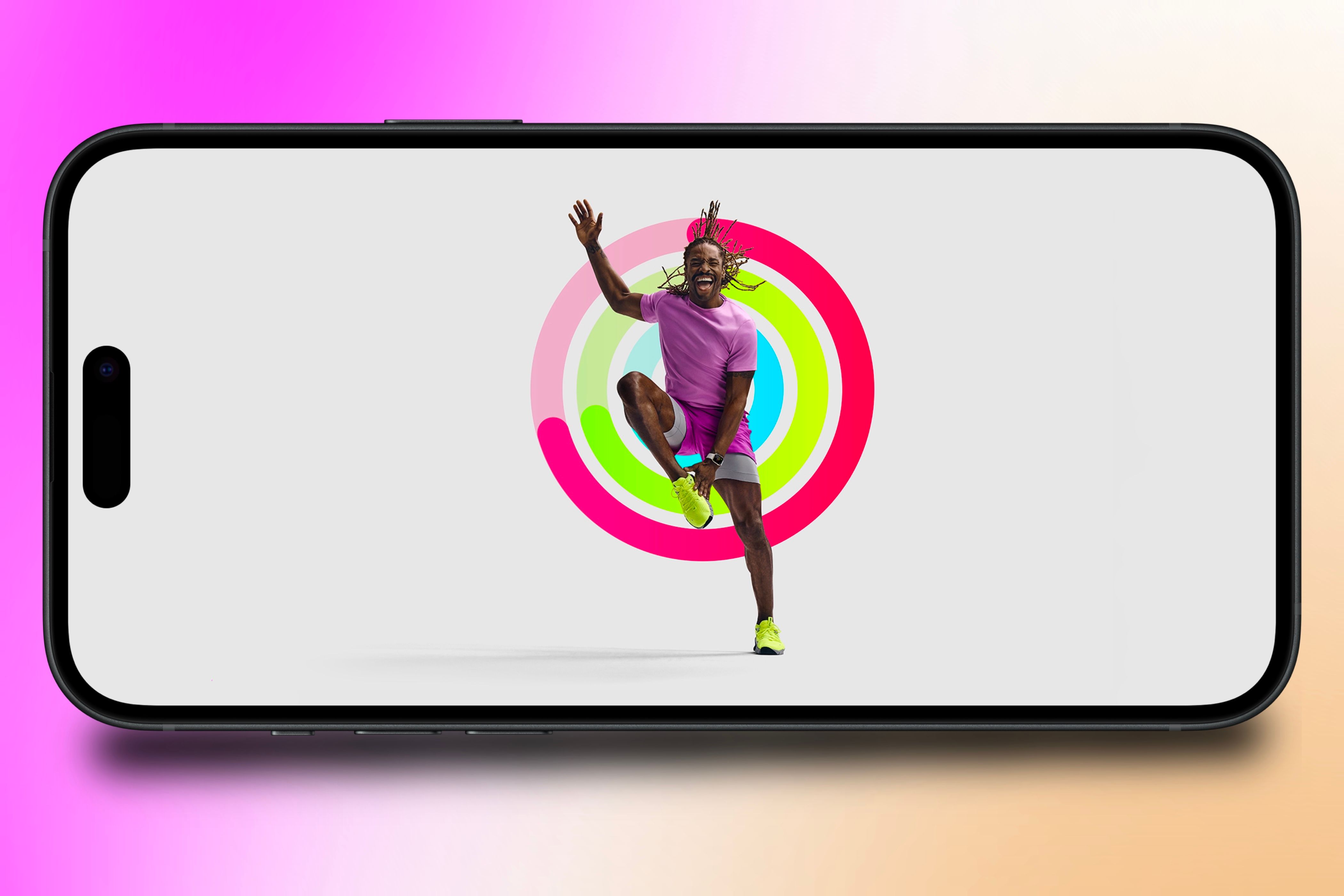 An Apple Fitness+ trainer working out in front of a set of Activity Rings showcased on an iPhone in front of a colorful background.