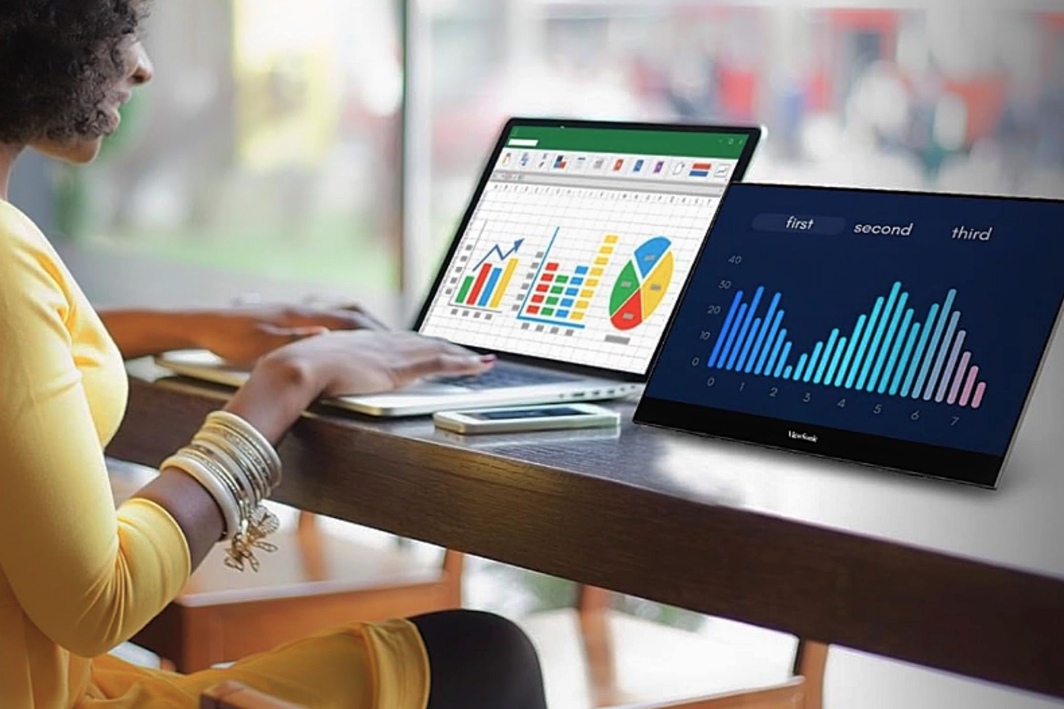 A woman works at a desk using the ViewSonic VX1655-4K OLED portable monitor.