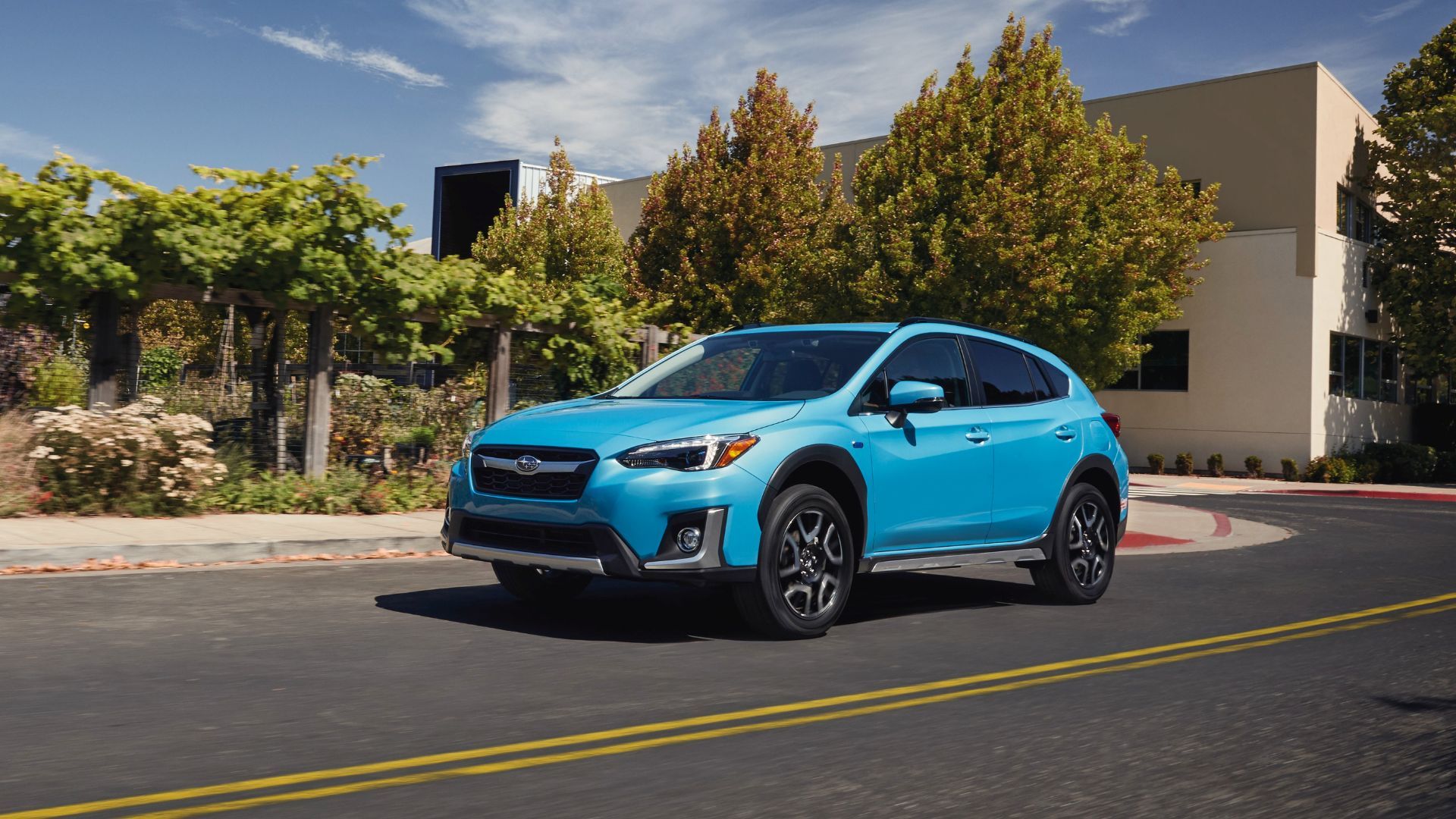 Full view of a blue 2020 Subaru Crosstrek Hybrid driving on a road through a city.