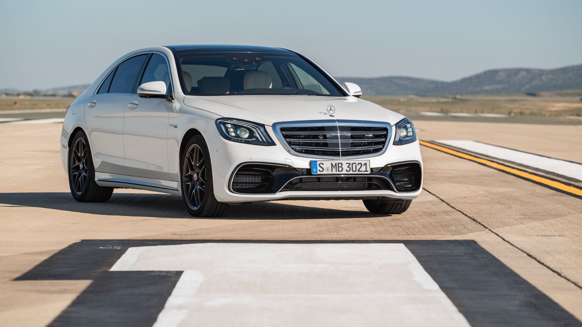 Full view of a white 2017 Mercedes-Benz S63 AMG parked on a runway. 