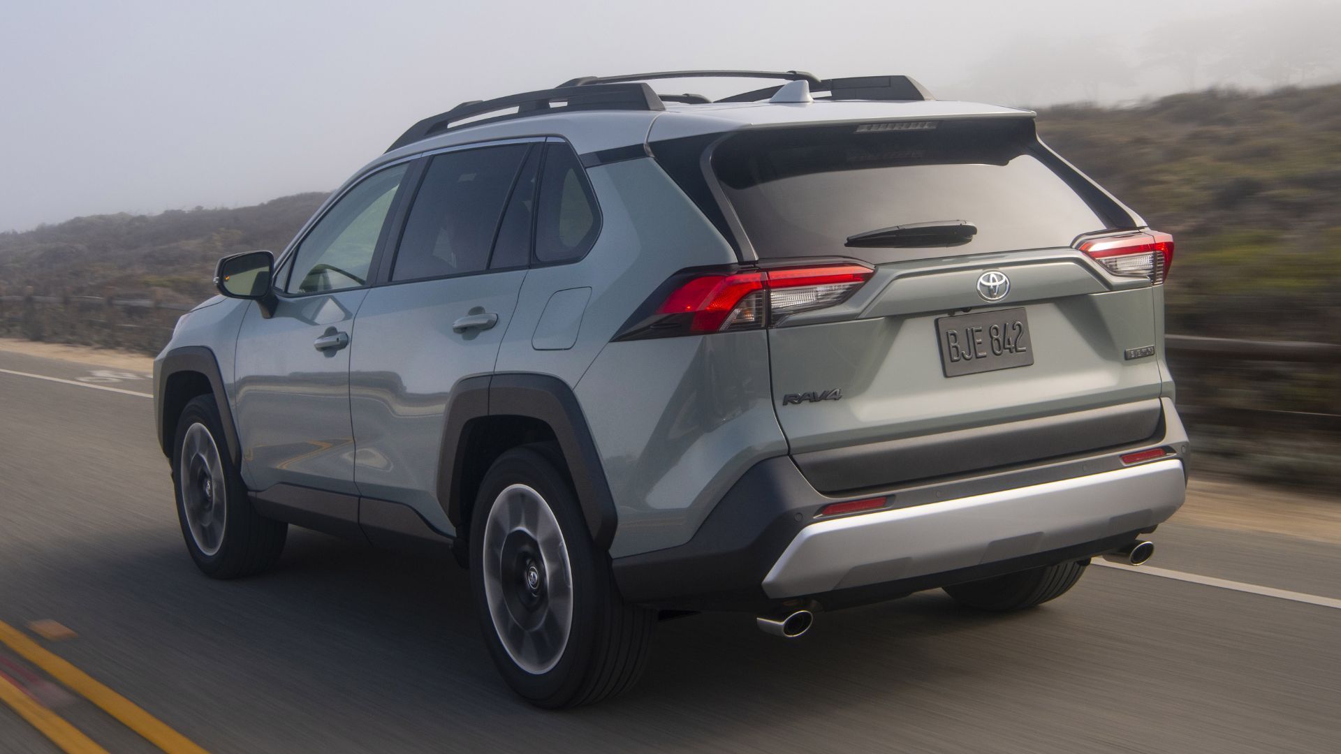 Rear of a gray 2020 Toyota RAV4 driving on a country road.