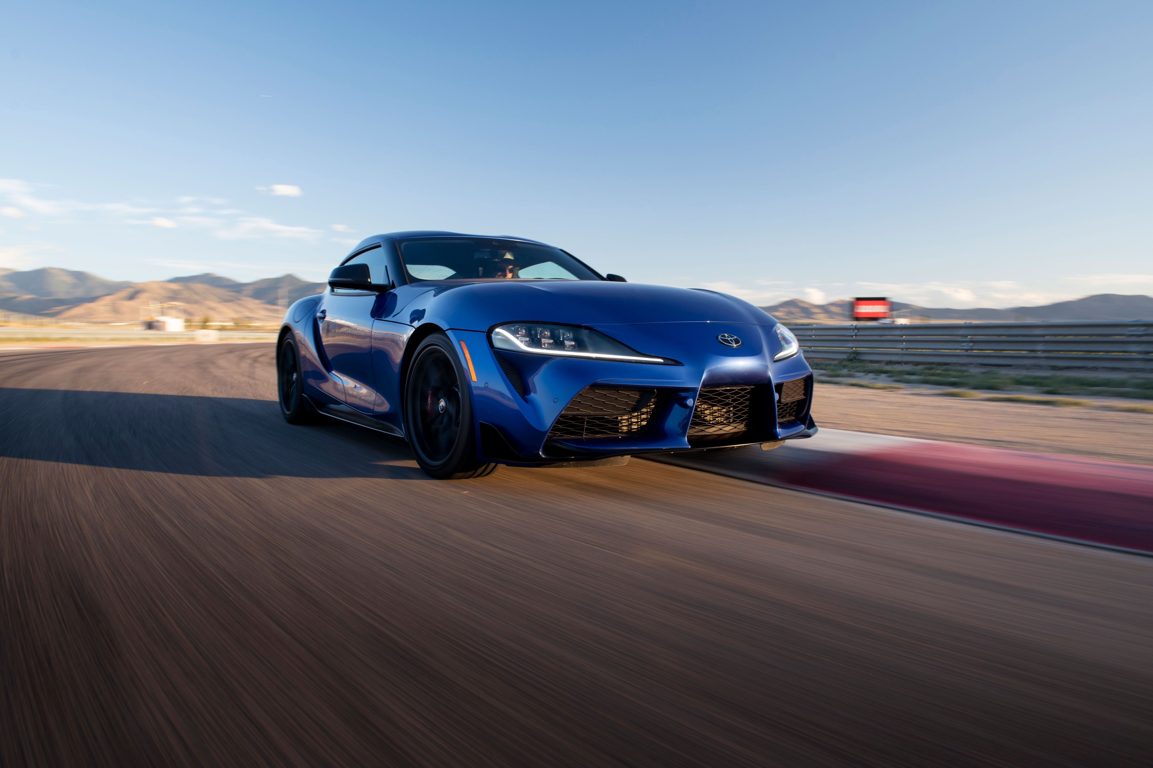 Full view of blue Toyota GR Supra on a race track. 