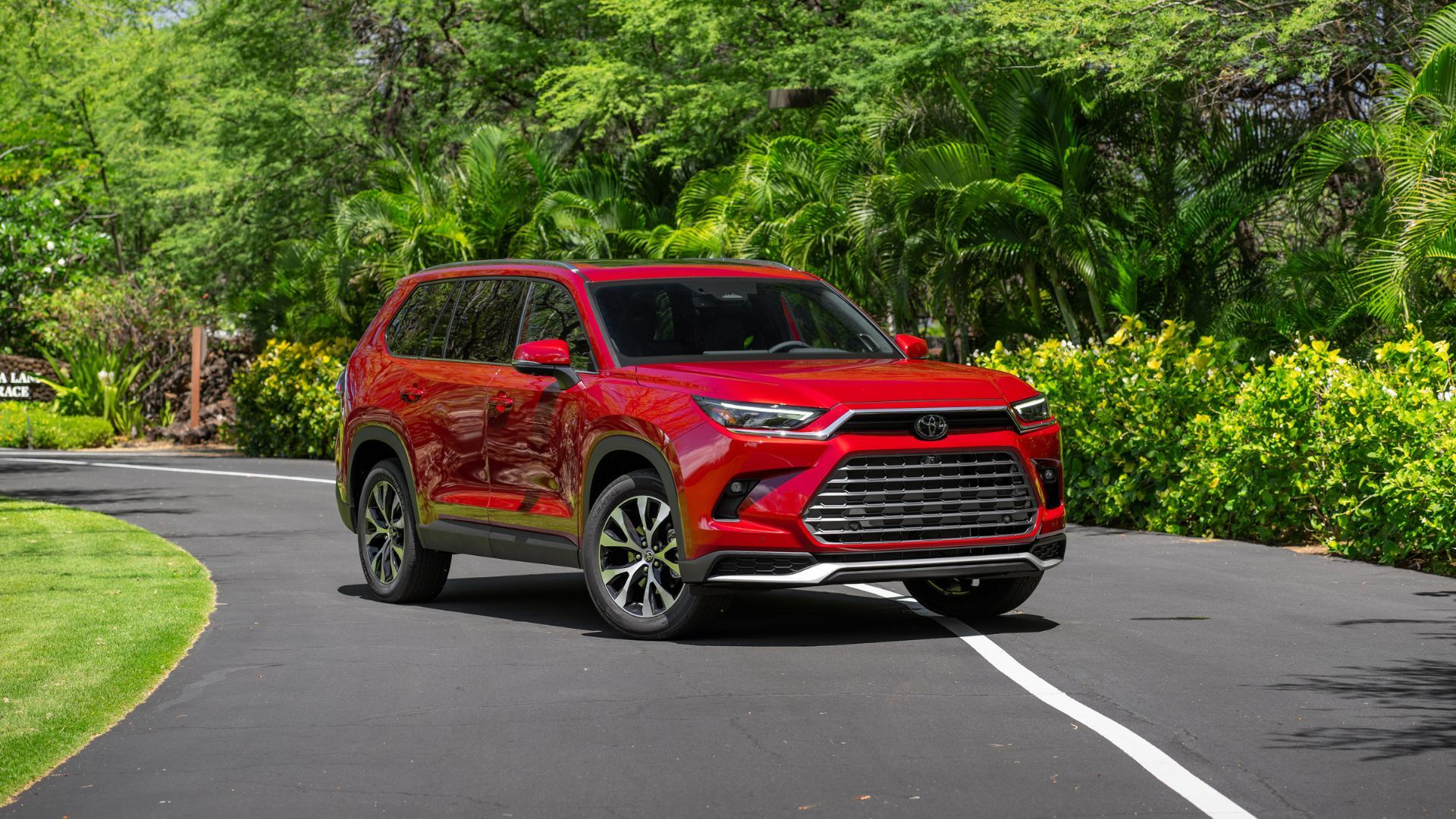 Full view of a red 2025 Toyota Grand Highlander parked sideways across a road.