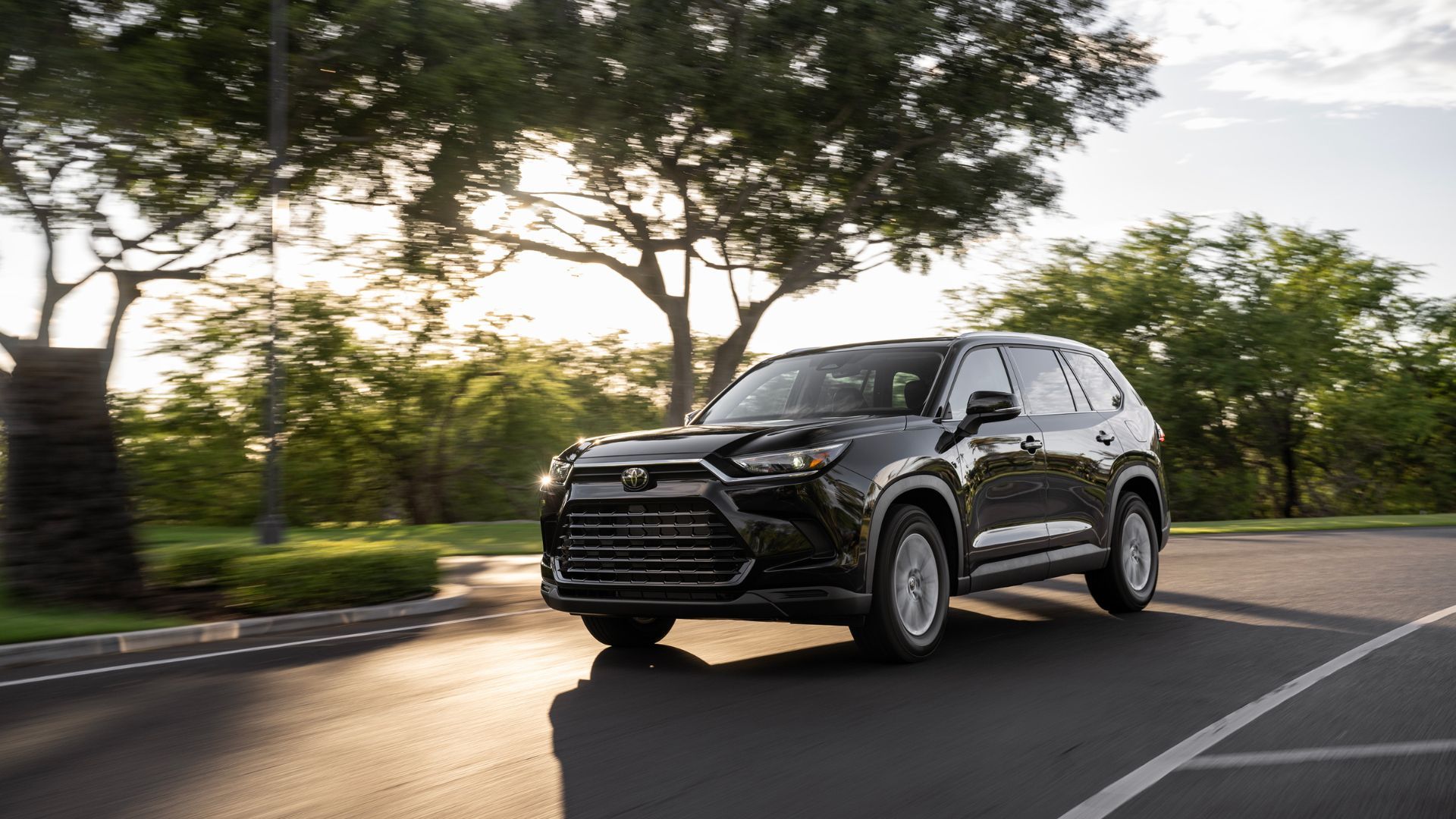 Full view of a black 2025 Toyota Grand Highlander driving.