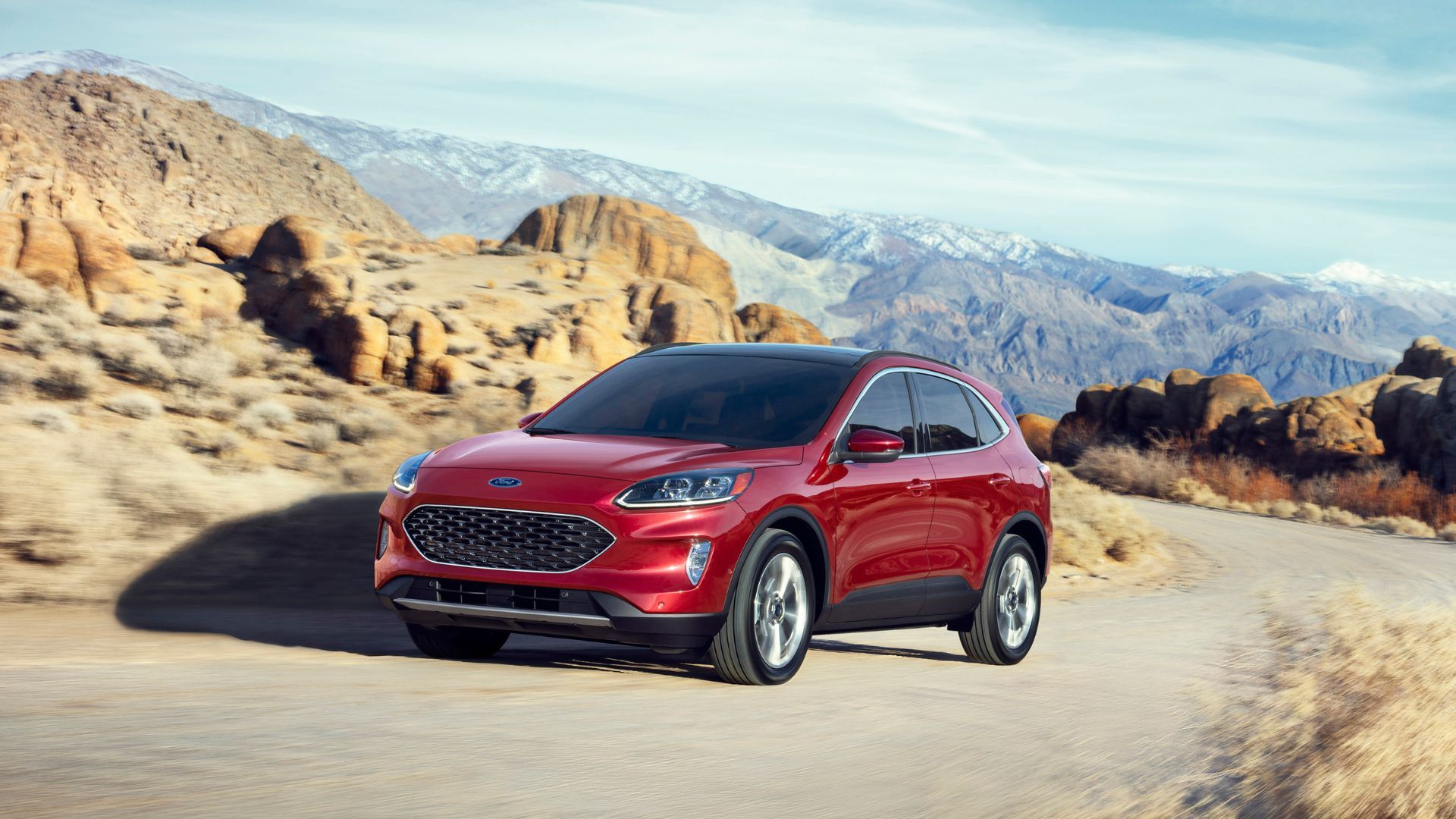 Front three-quarter view of a red 2020 Ford Escape Hybrid driving up a winding country pass.