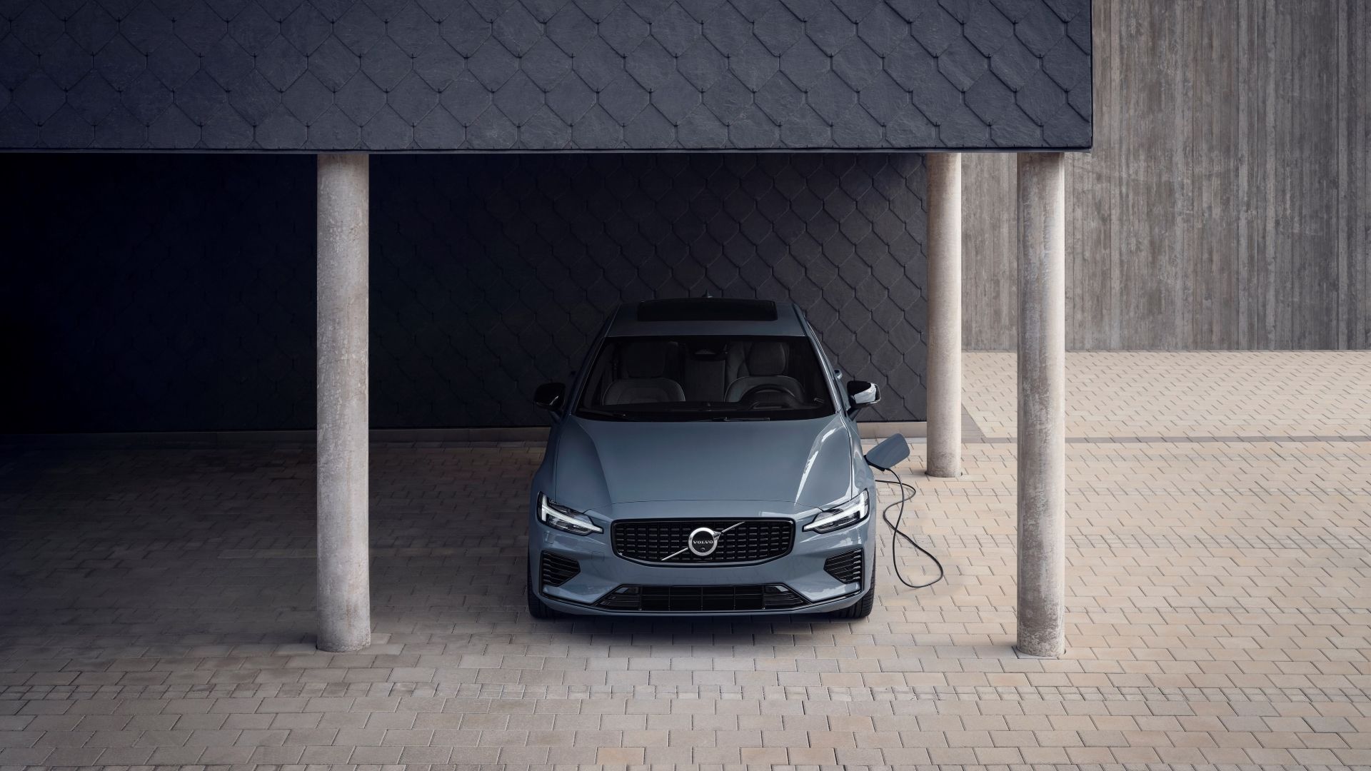 A head-on shot of a 2025 Volvo S60 hooked up to a charger