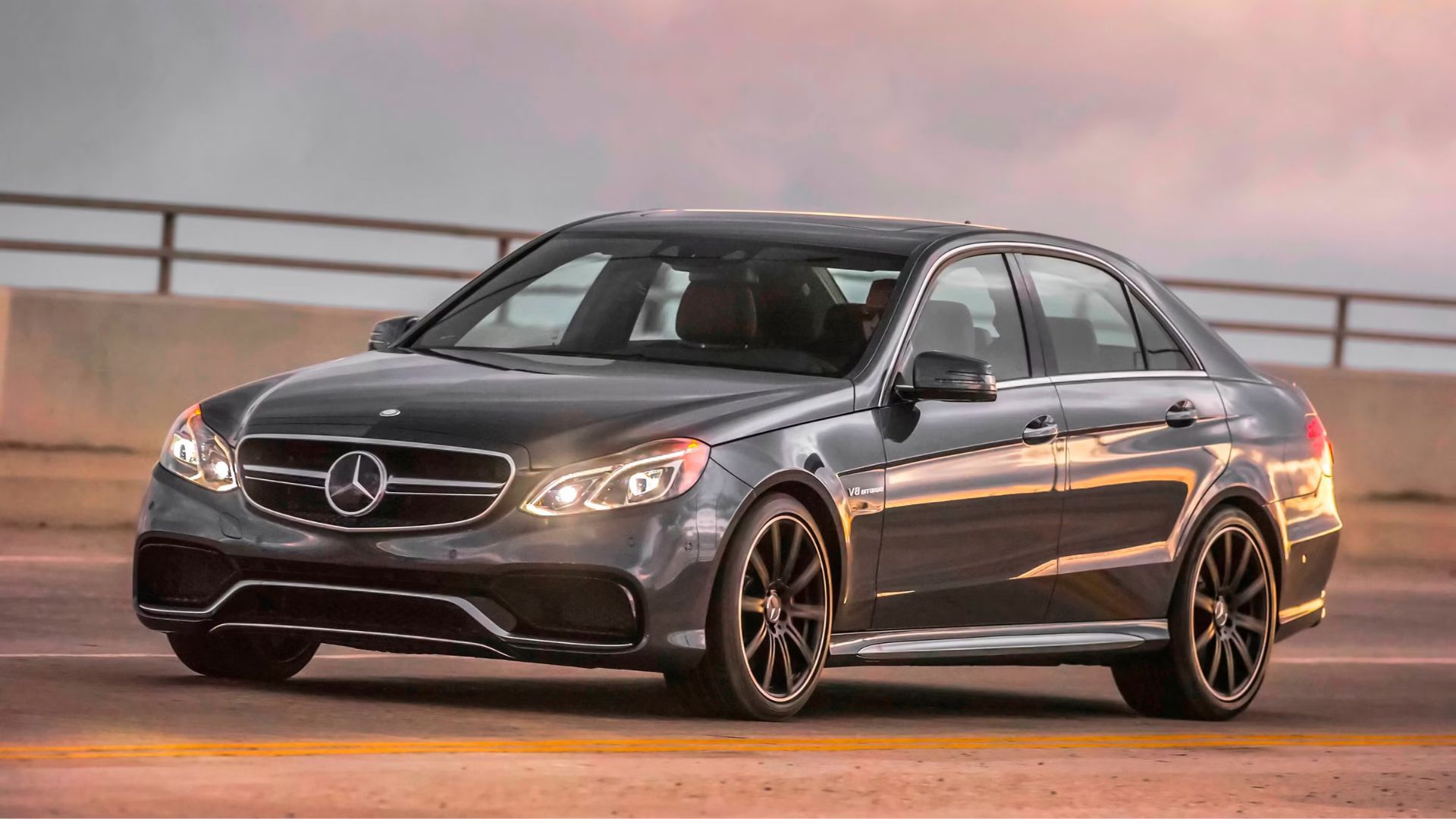 Full view of a gray Mercedes-Benz E63 AMG driving over a bridge.