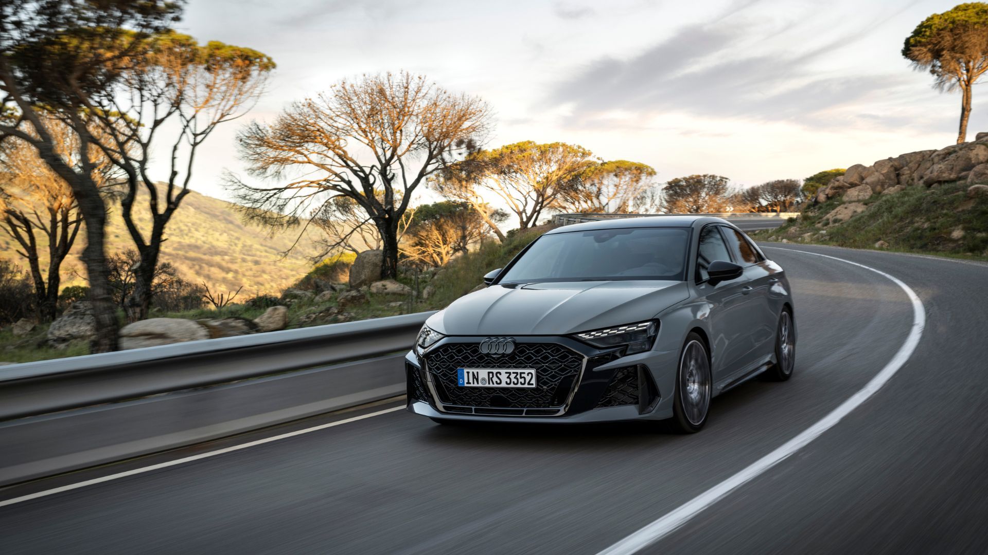 Full view of gray Audi RS3 Sedan on a winding country road.