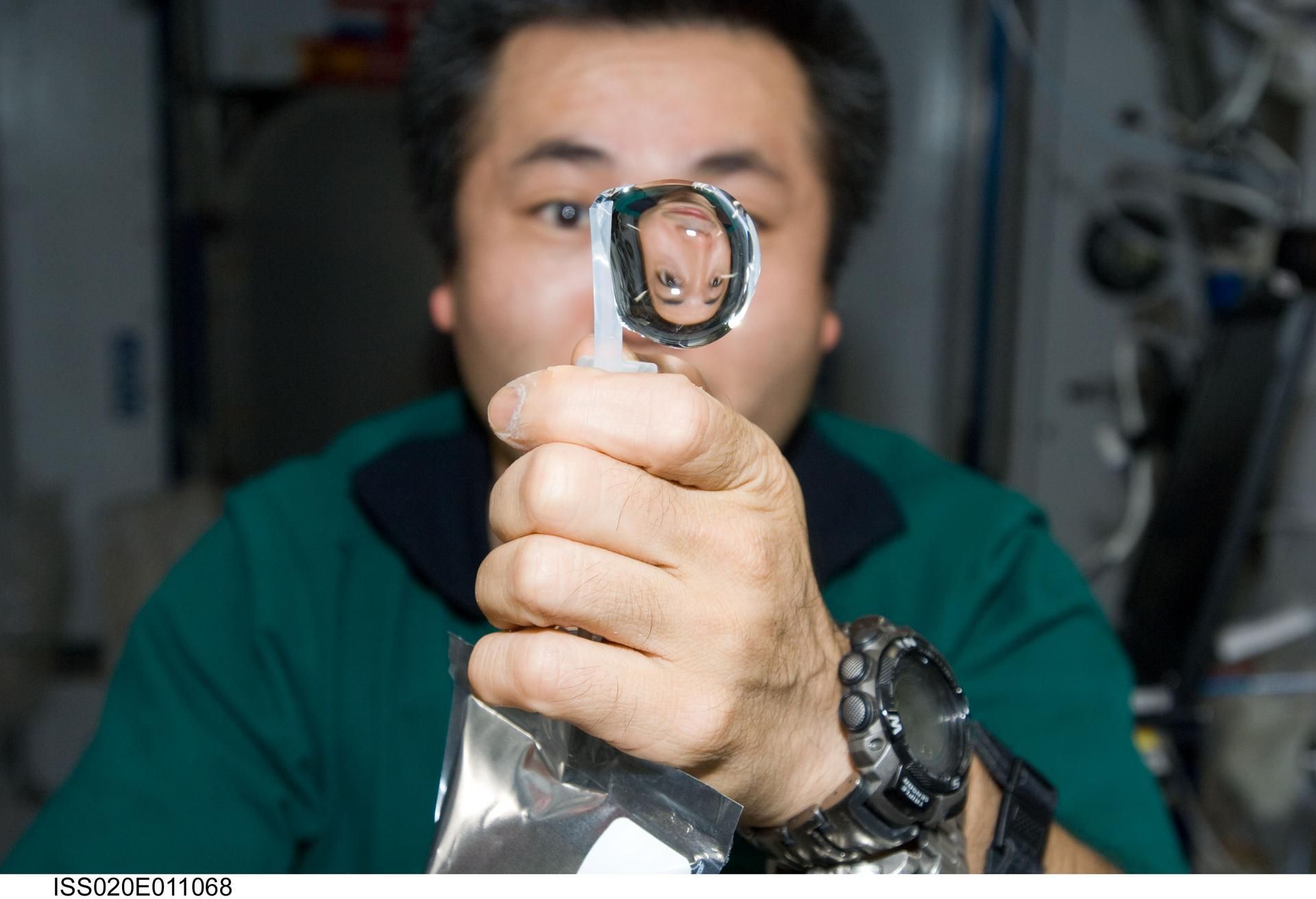 An astronaut squeezing a water bubble out of his beverage container.