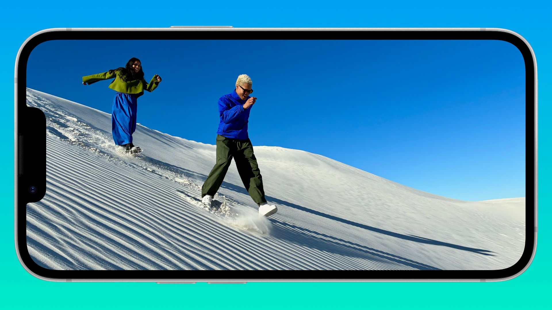 iPhone 16e in landscape mode, displaying an image of a young man and woman sandwalking in the desert.