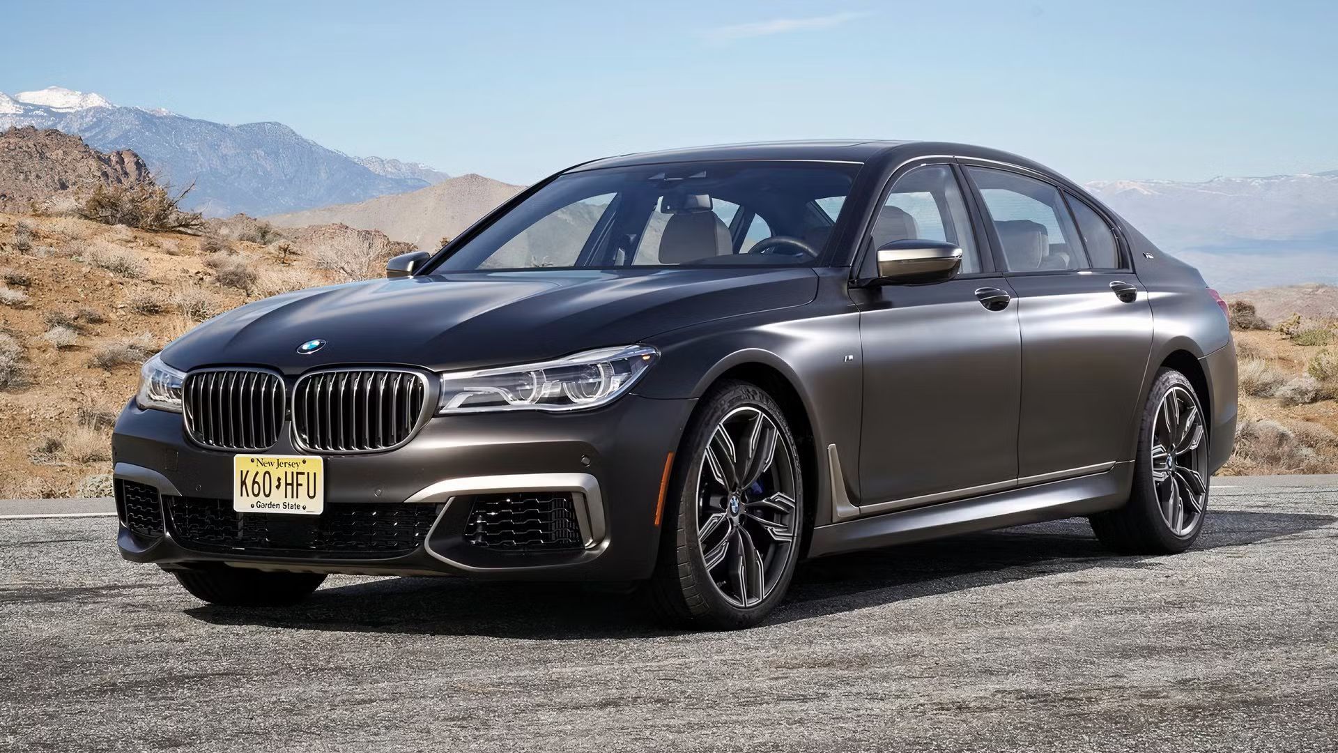 Full view of a gray BMW M760i xDrive parked on tarmac in the desert. 